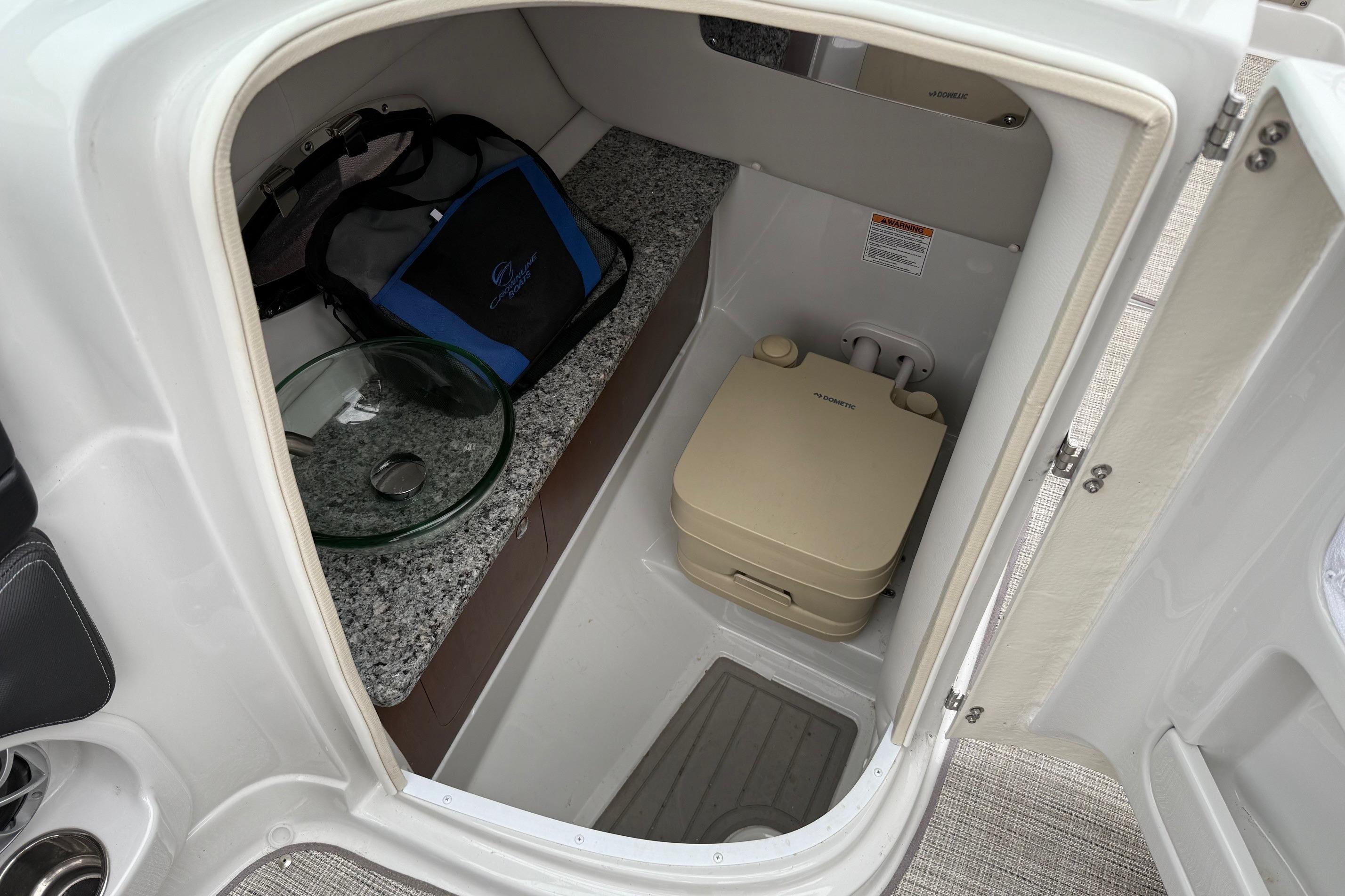 2022 Crownline 255 SS boat interior with compact bathroom and storage area.