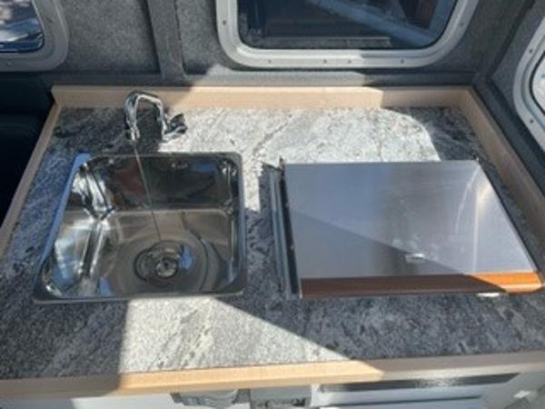 Compact kitchen area in 2025 Spartan 2600 Olympia RV with sink and stove.