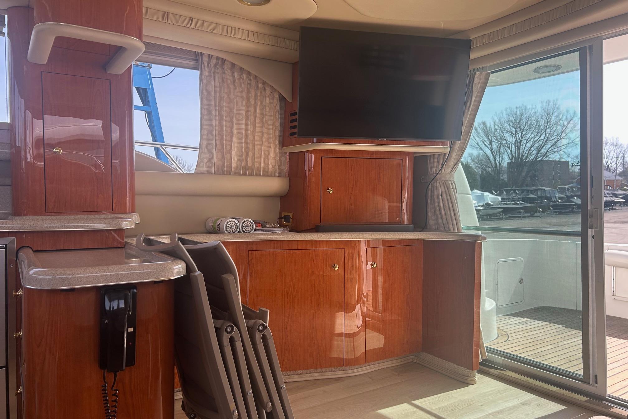 Interior of 2000 Sea Ray 480 Sedan Bridge yacht with wood cabinetry and large TV.