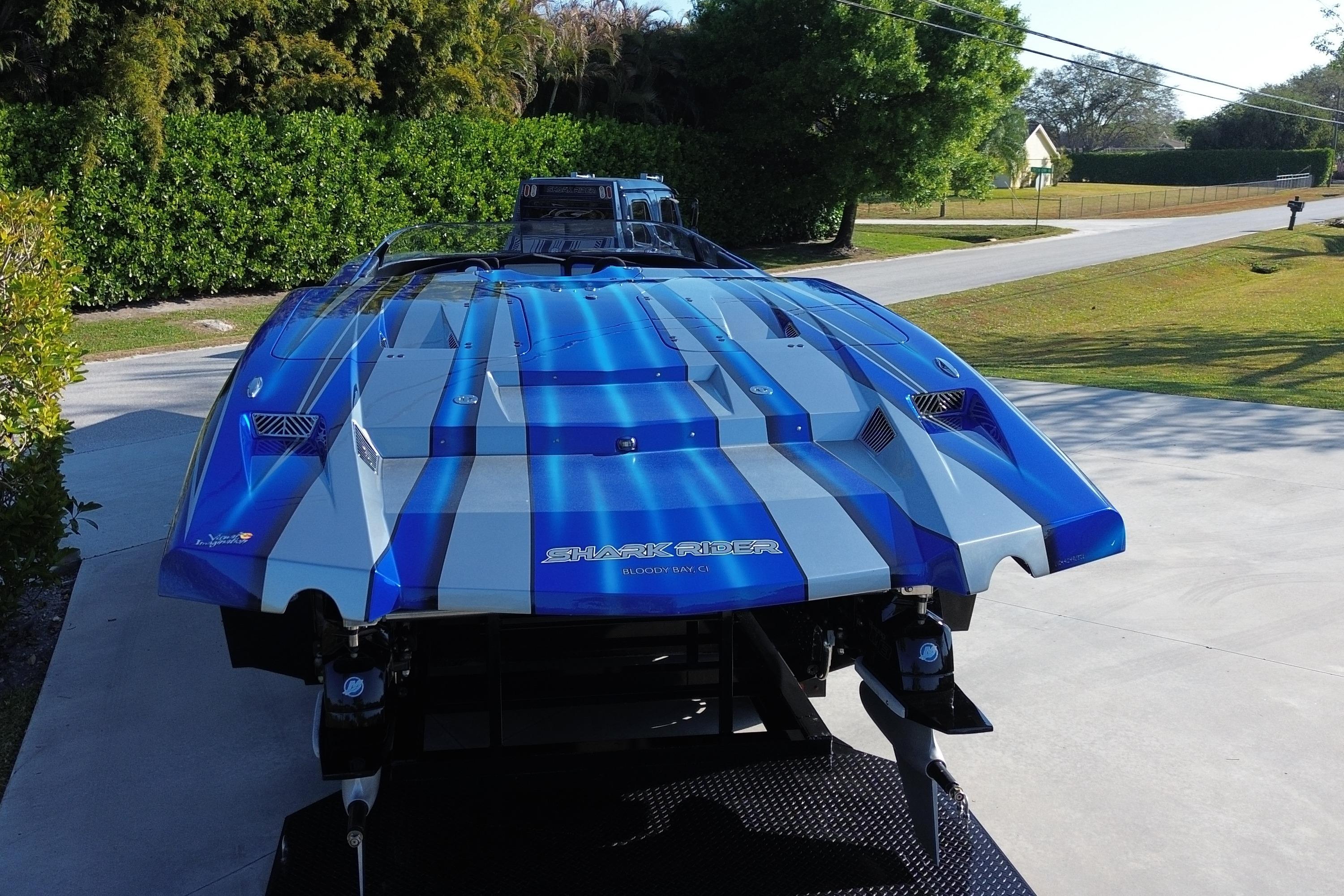 Blue and silver MTI 44 RP speedboat parked on a driveway, rear view.