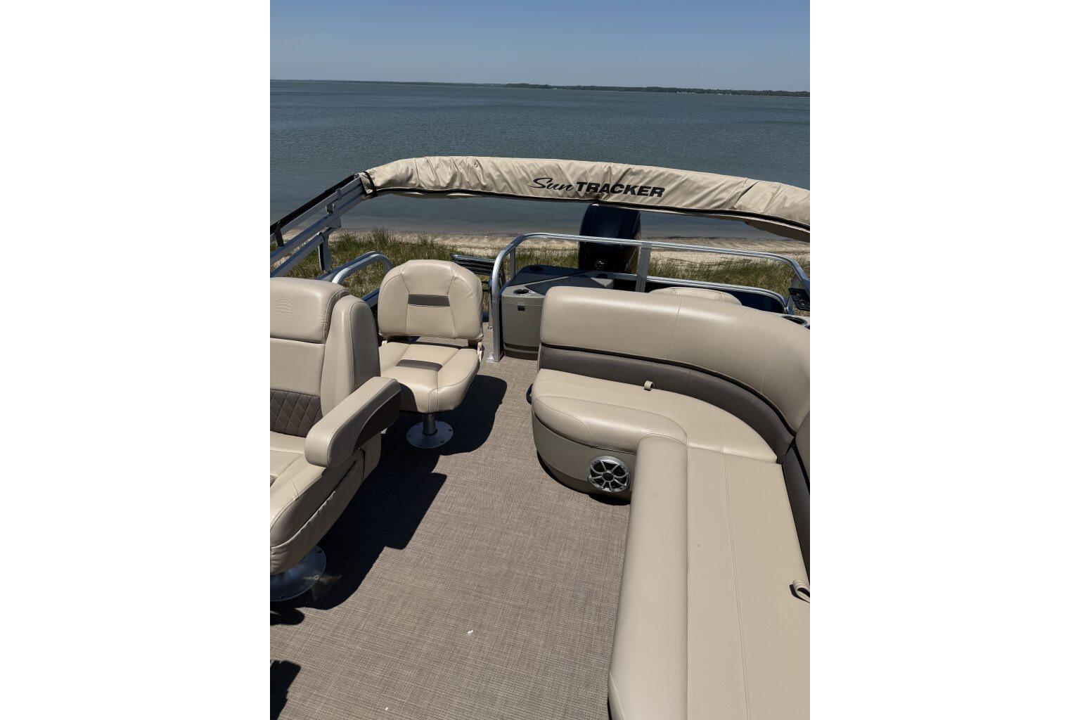 2024 Sun Tracker Bass Buggy 18 DLX pontoon boat interior with seating, overlooking serene water.