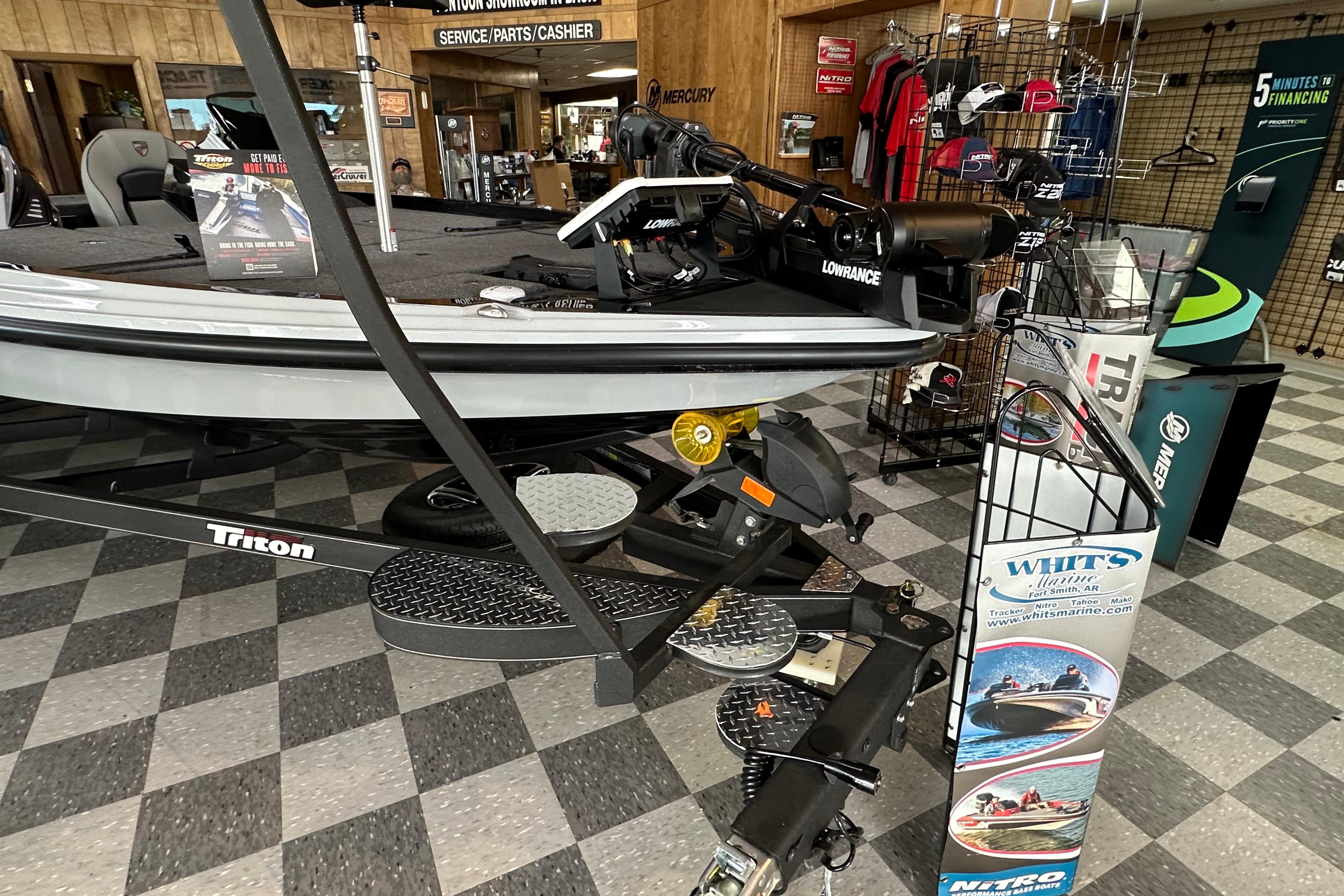 2024 Triton 20XP Patriot boat displayed in showroom with accessories and promotional materials.