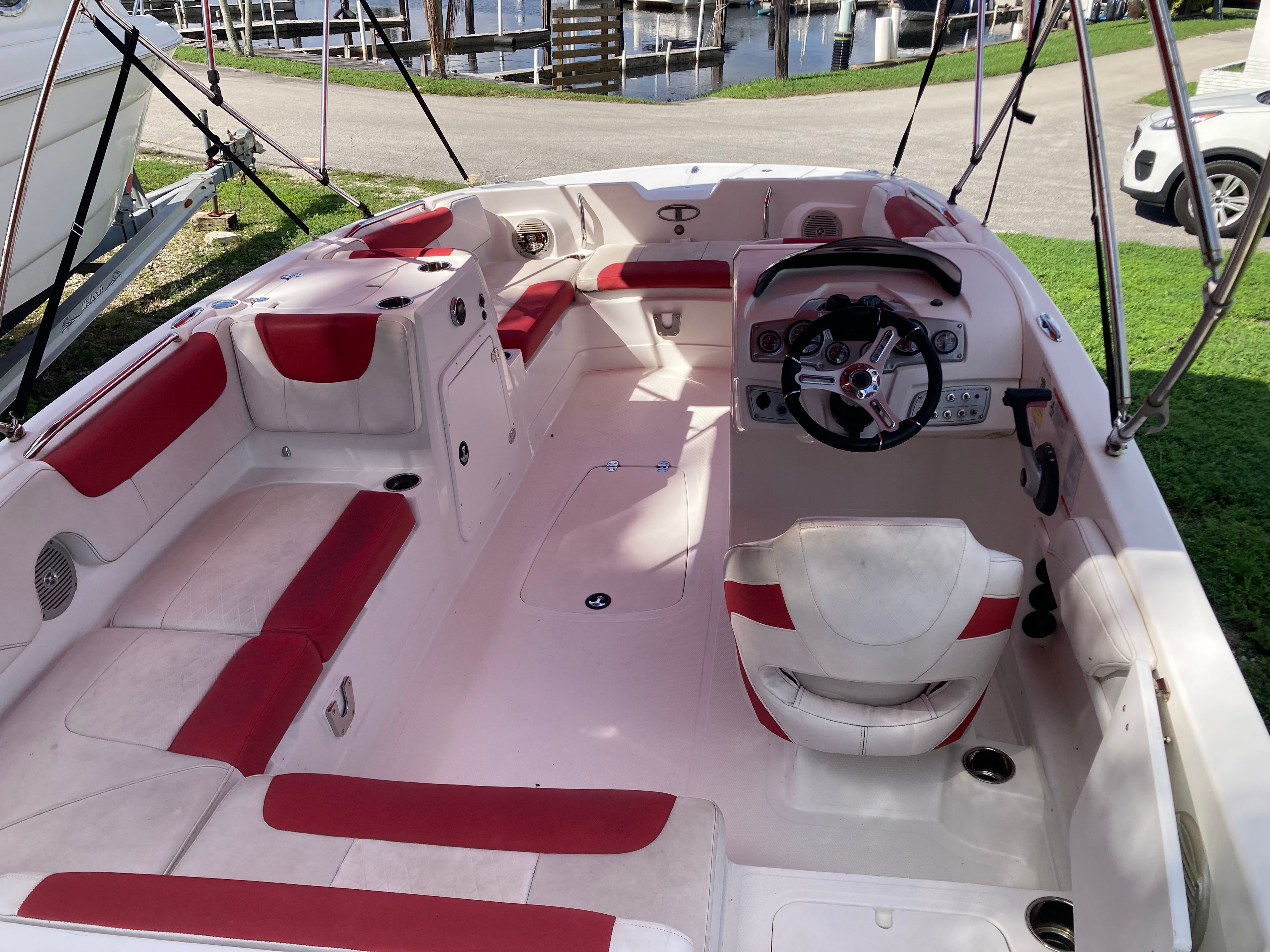 The image shows the cockpit of a 2019 Tahoe 21.5 boat with red and white seating.