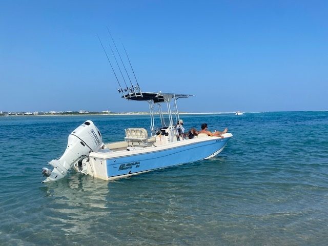 A 2022 Carolina Skiff 21 Ultra Elite boat on calm blue water with fishing rods.