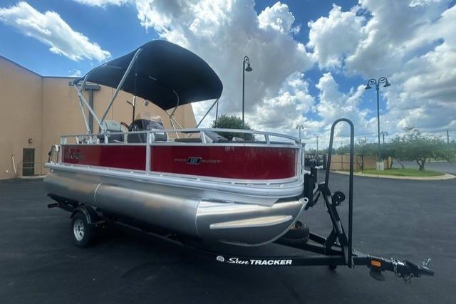 2026 Sun Tracker Bass Buggy 18 DLX pontoon boat with canopy on trailer under cloudy sky.