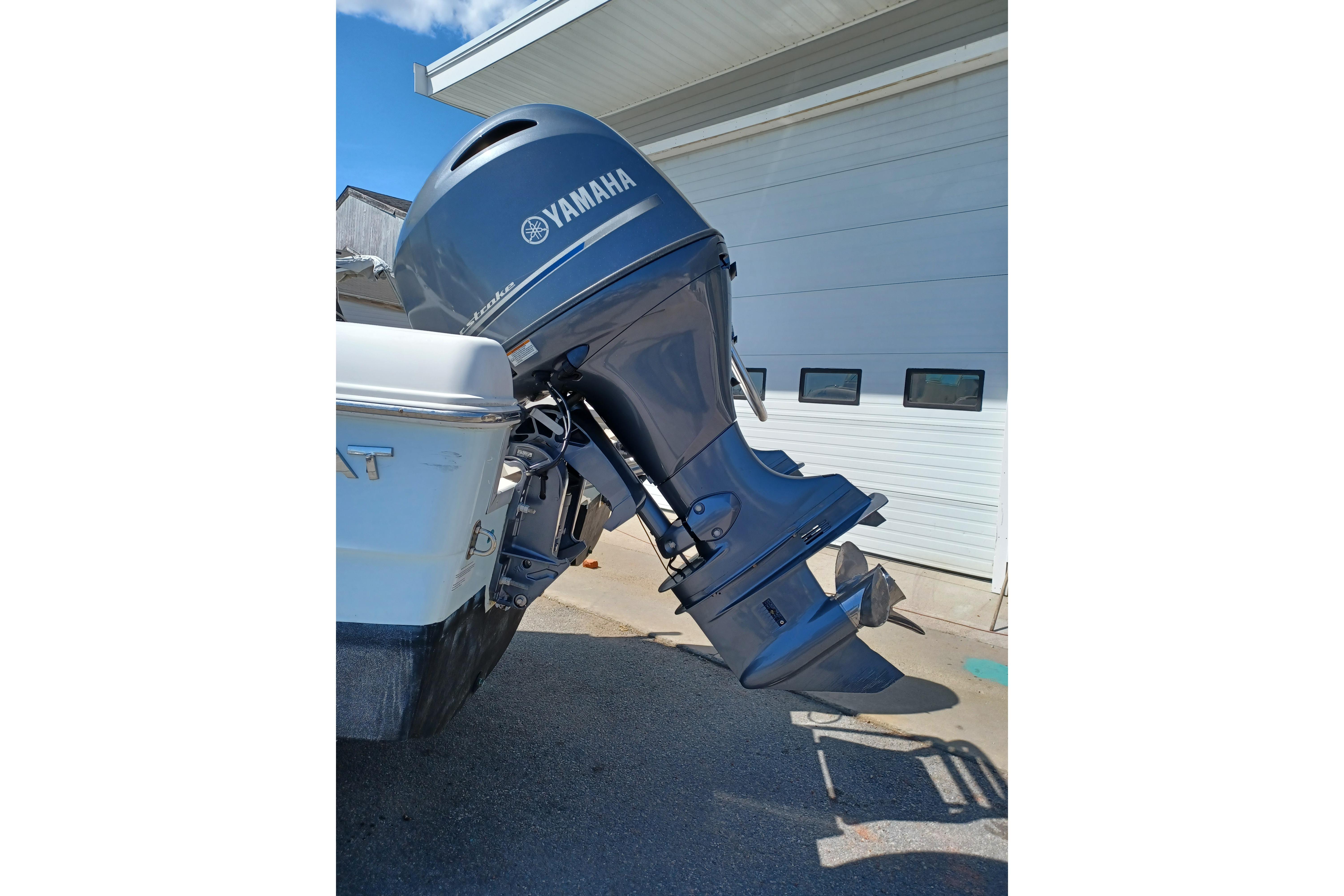 Yamaha outboard motor on a 2020 World Cat 230 DC boat, parked near a garage.