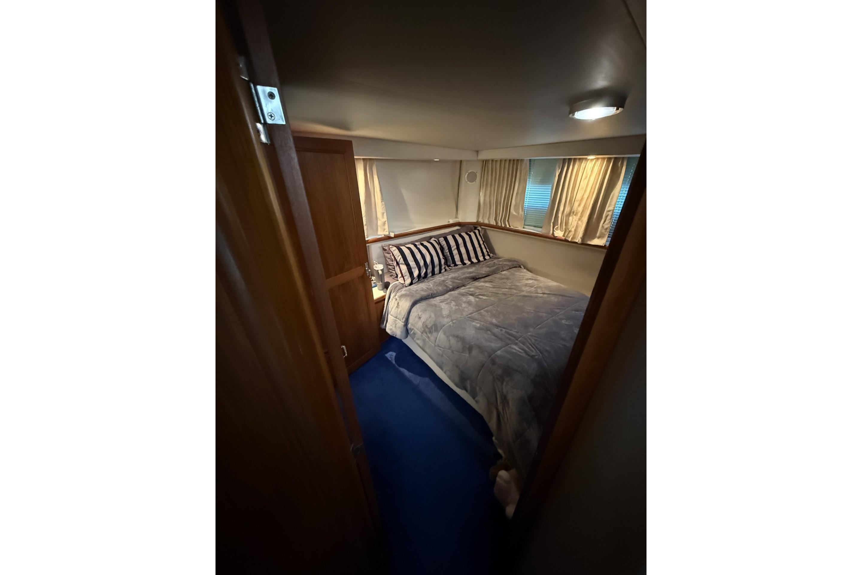 Cozy bedroom in 1993 Carver 350 Motor Yacht with striped pillows and curtains.