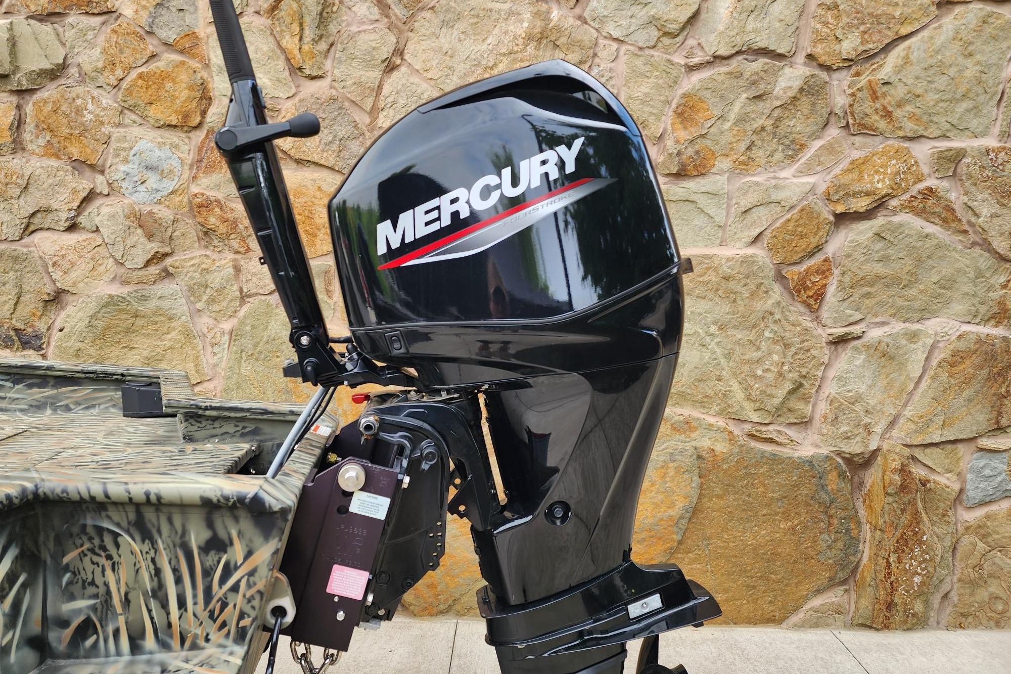 Outboard motor on 2026 Tracker Grizzly 1650 T Prairie Wings Edition boat, stone wall background.