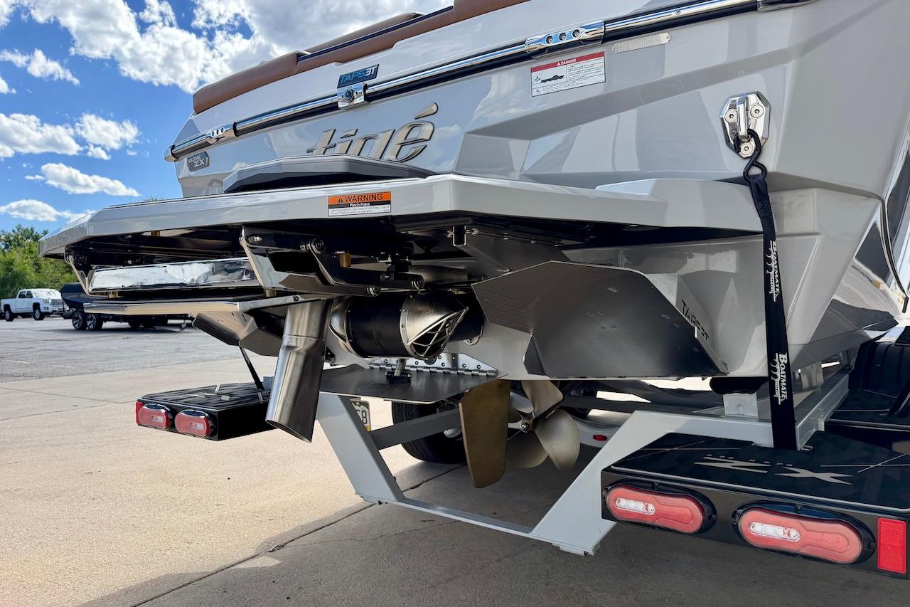 2025 Tigé Ultré 25ZX boat rear view, showcasing propeller and exhaust system under a clear sky.