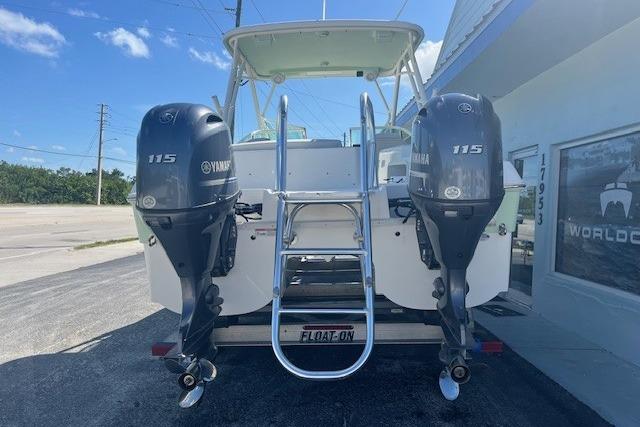 2024 World Cat 230 SD boat with dual Yamaha 115 engines, parked outside a building.