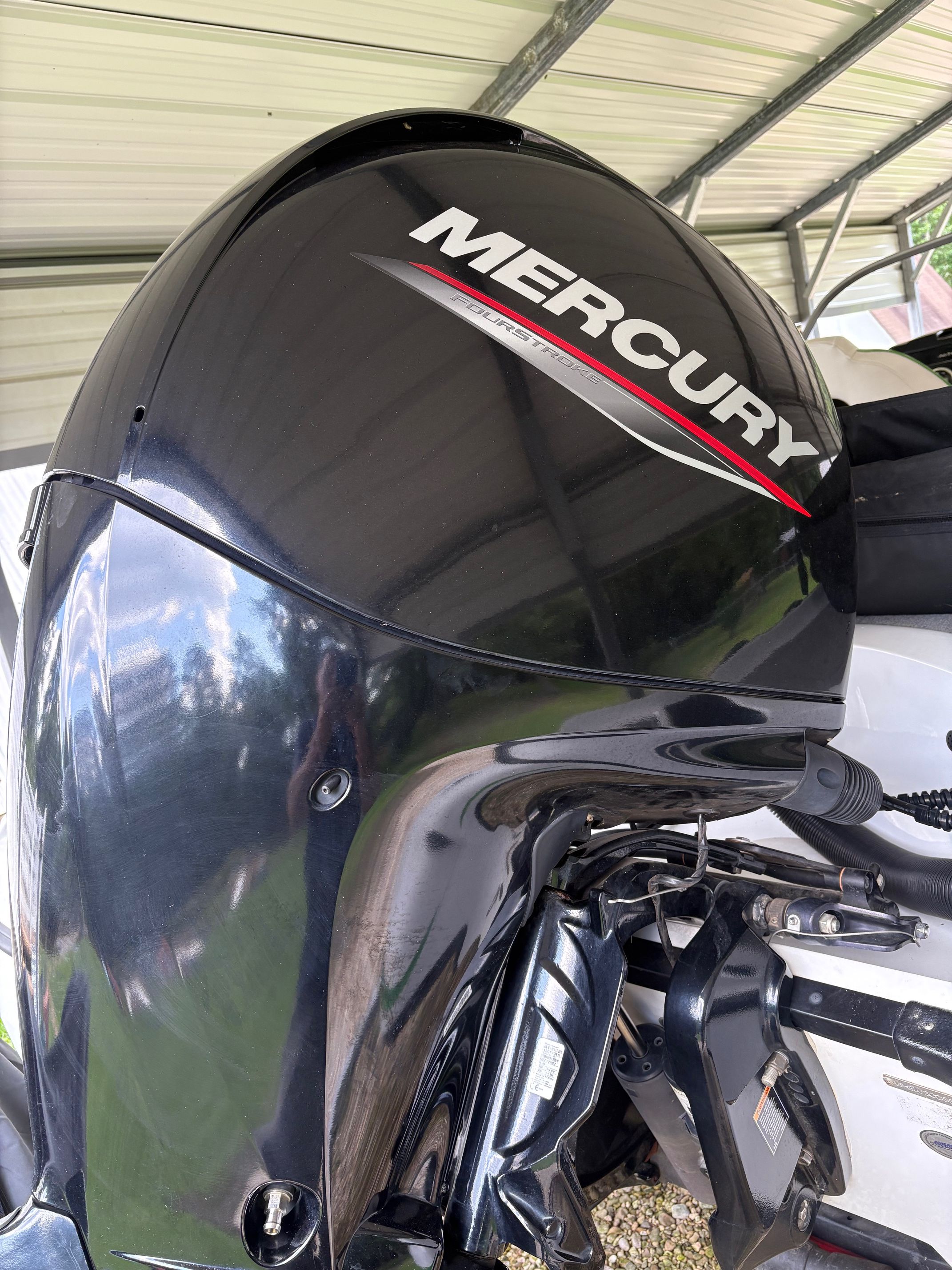 A Mercury outboard motor is attached to a boat, situated in a covered area.