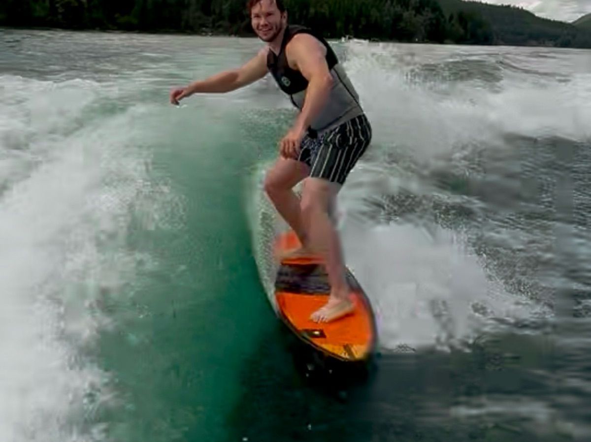 A man surfing behind a boat on a large wave.
