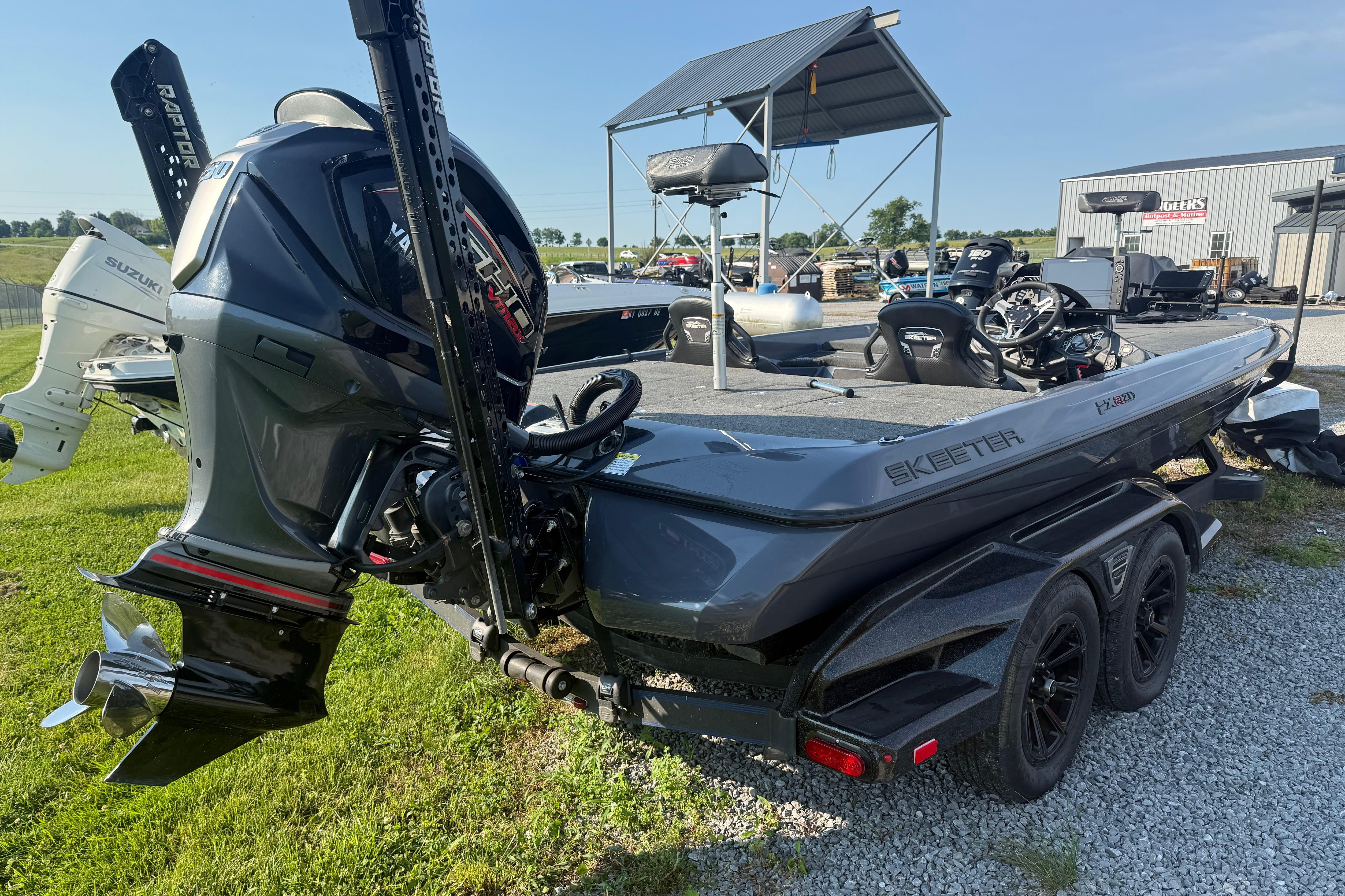 2024 Skeeter FXR21 boat with Yamaha outboard motor, parked on grass near dealership.