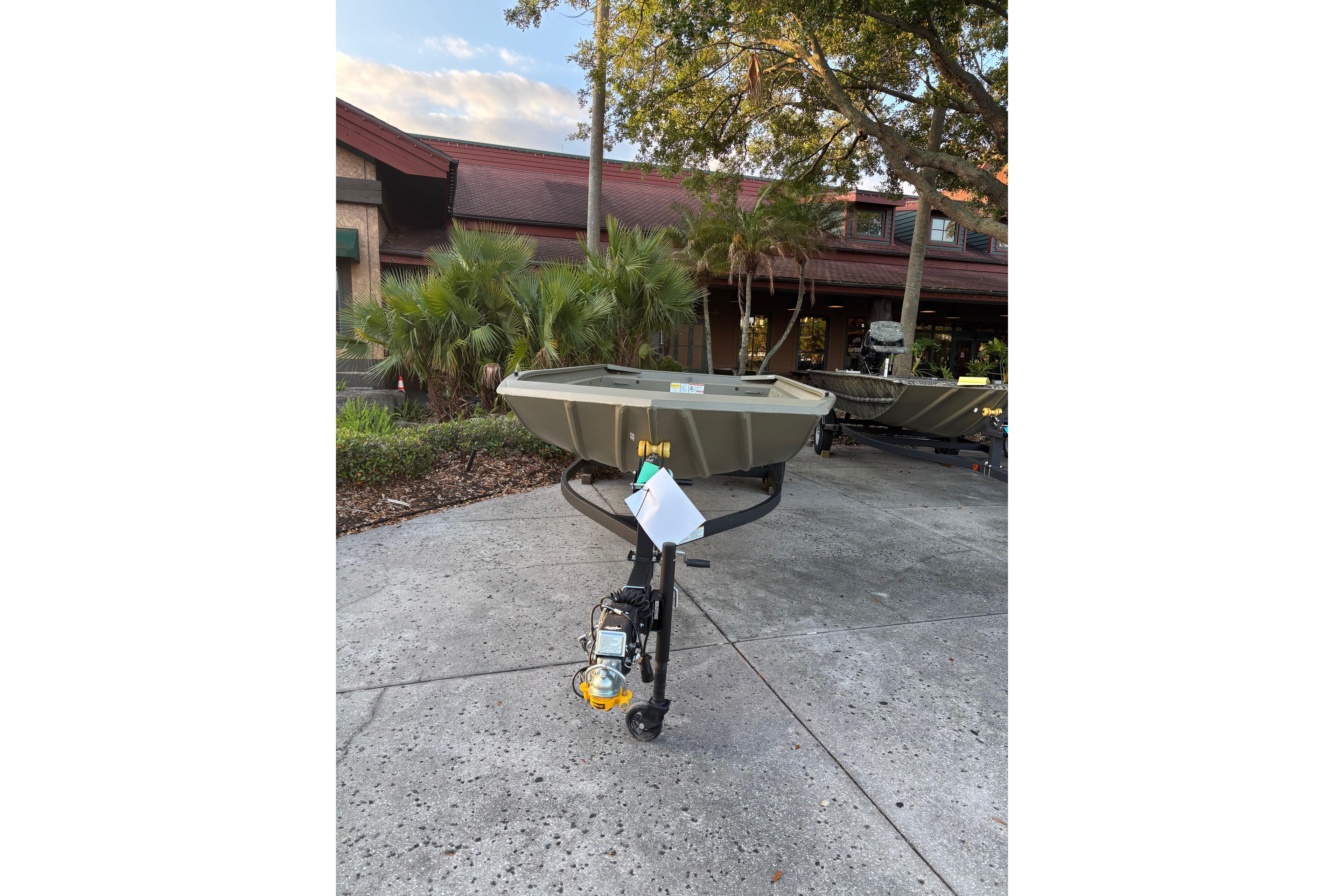 2026 Tracker Grizzly 1860 Utility boat on trailer, outdoor setting with trees and building.