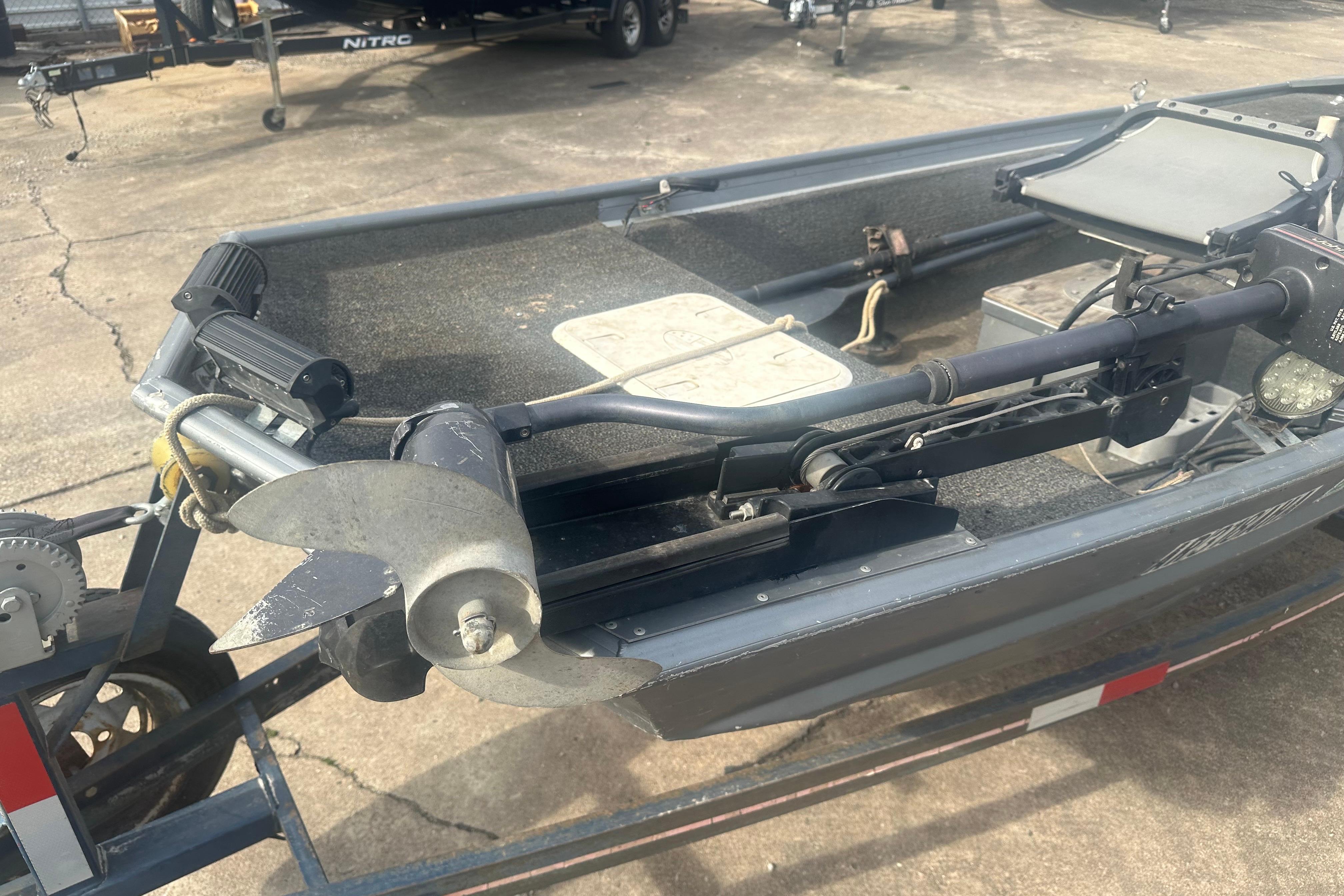 1991 Grumman Rogue 150 T boat with motor and trailer, parked on concrete.