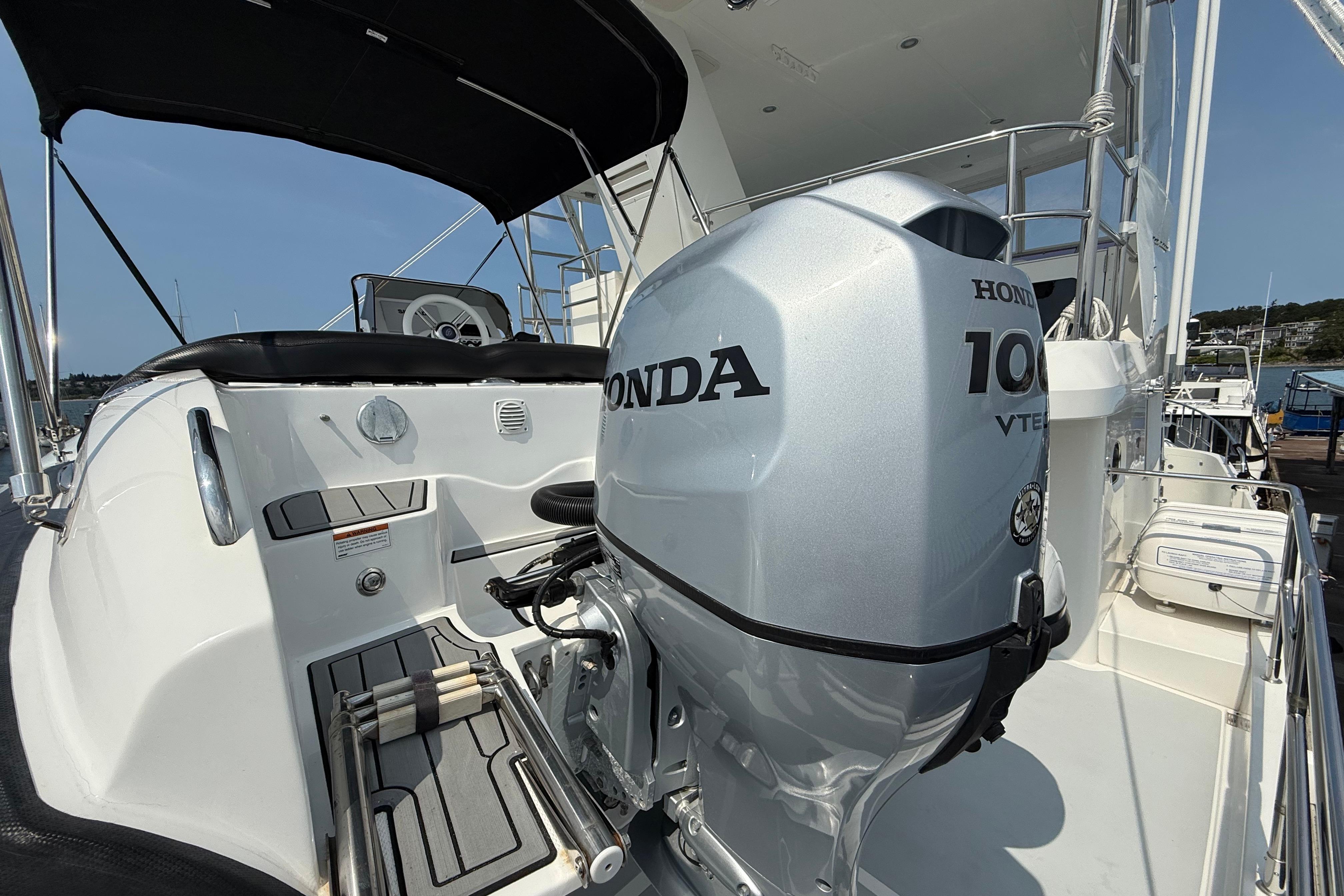 2009 Nordhavn N64 yacht with Honda 100 VTEC outboard motor, docked under clear skies.