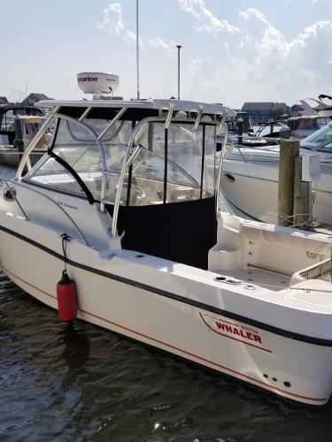 2011 Boston Whaler 235 Conquest boat docked in marina, clear skies above.