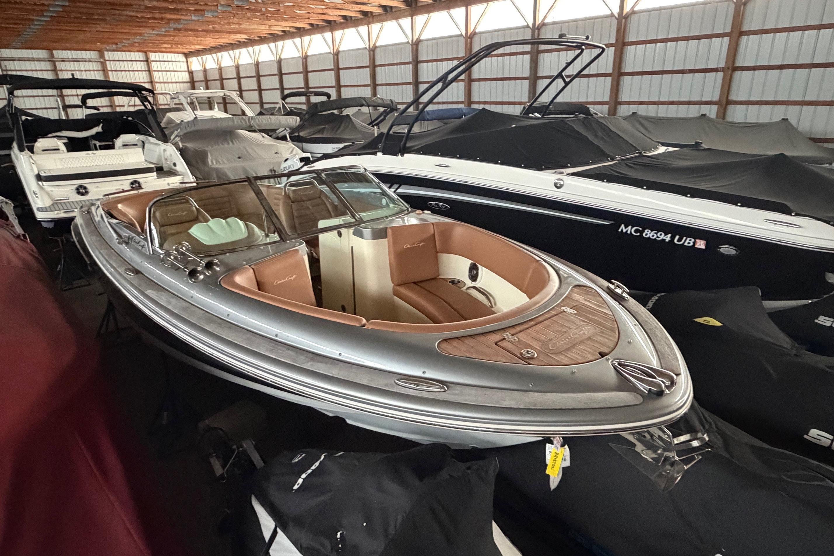 2013 Chris-Craft Launch 25 boat in storage, surrounded by covered vessels.
