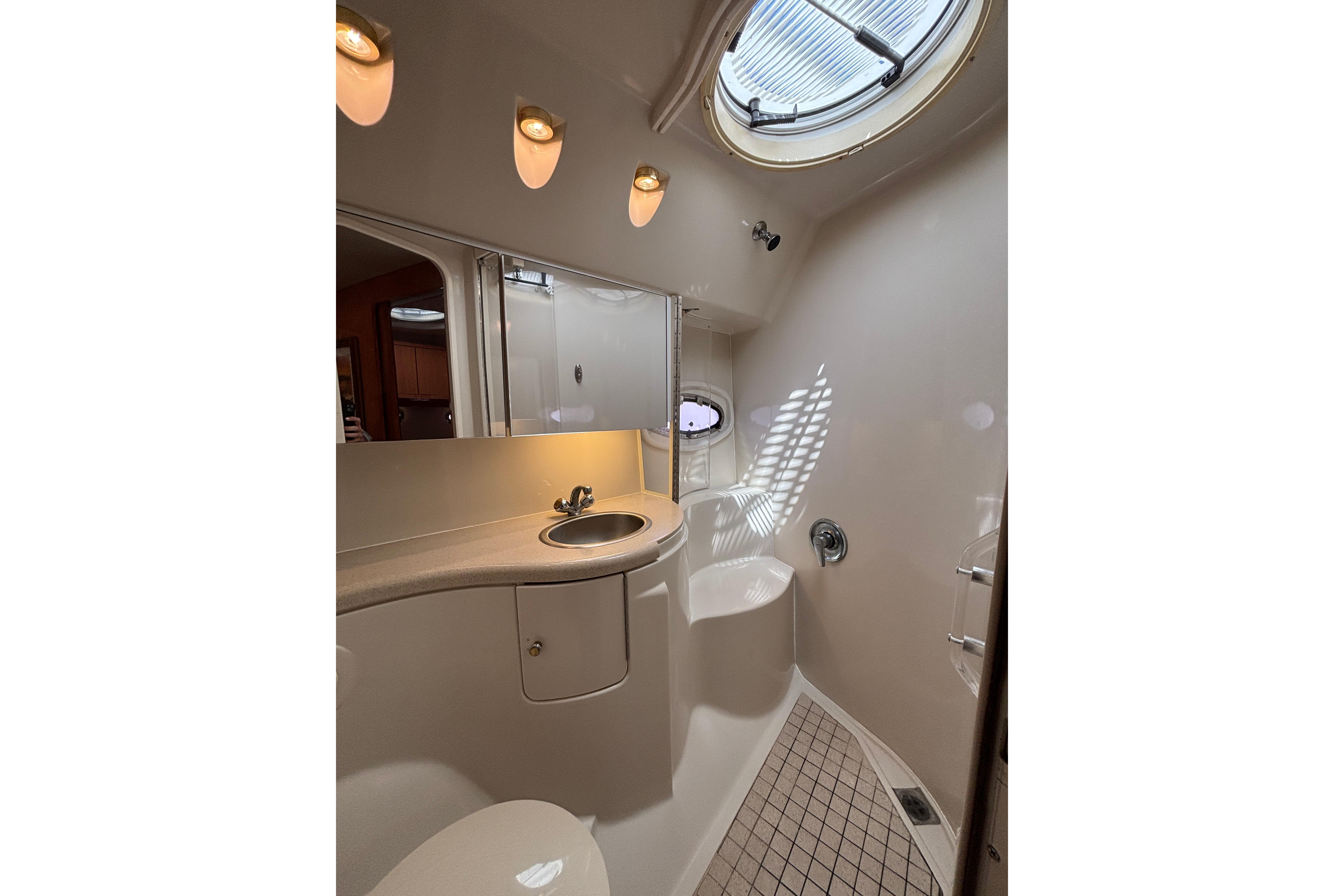 Luxurious bathroom in 2000 Regal Commodore 4160 yacht with modern fixtures and porthole window.