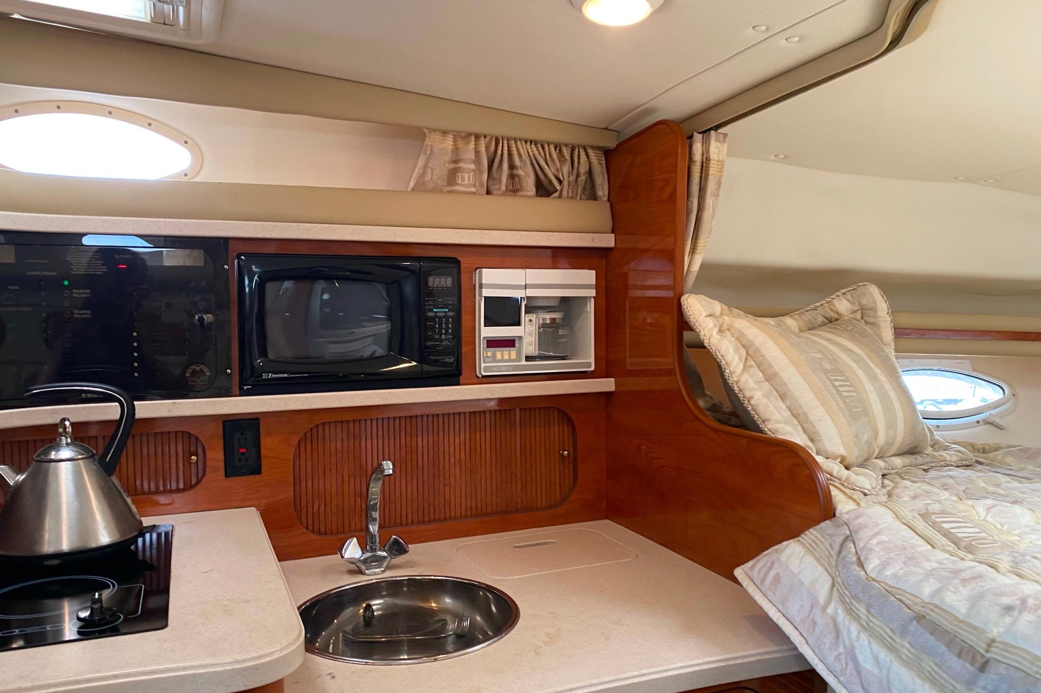 Interior of 2003 Rinker Fiesta Vee 342 boat with kitchenette and cozy sleeping area.