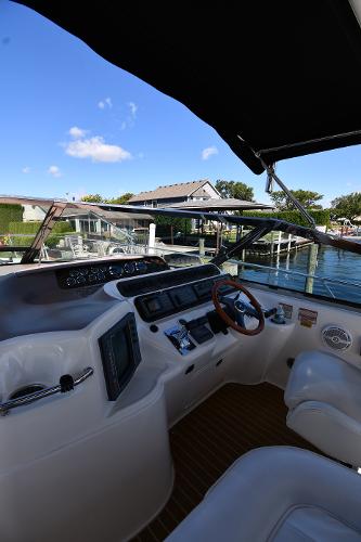 1997 Sea Ray 400 Sundancer helm with modern controls, docked by a scenic waterfront.