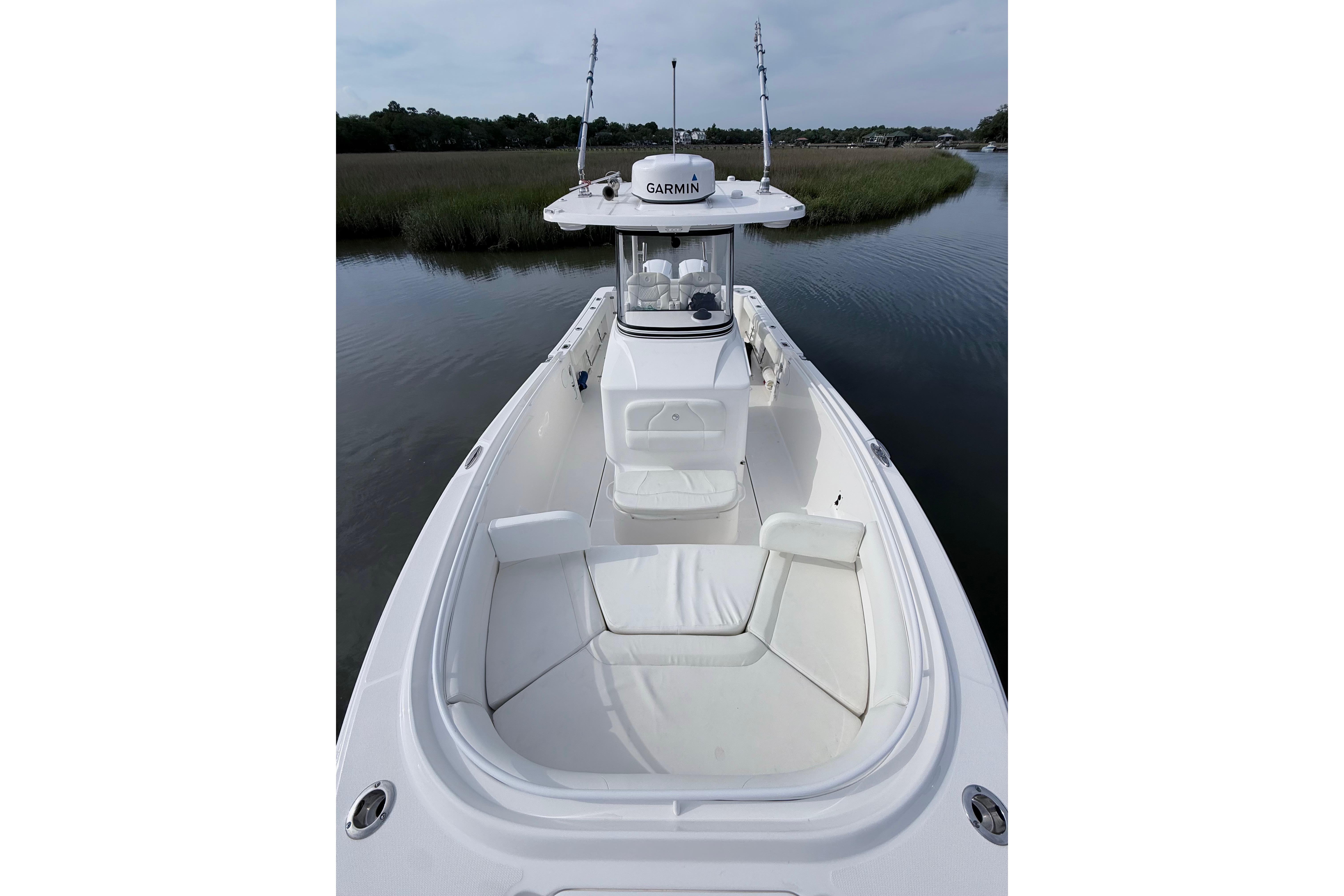 2022 Edgewater 280CC boat with white seating, navigating a calm waterway.