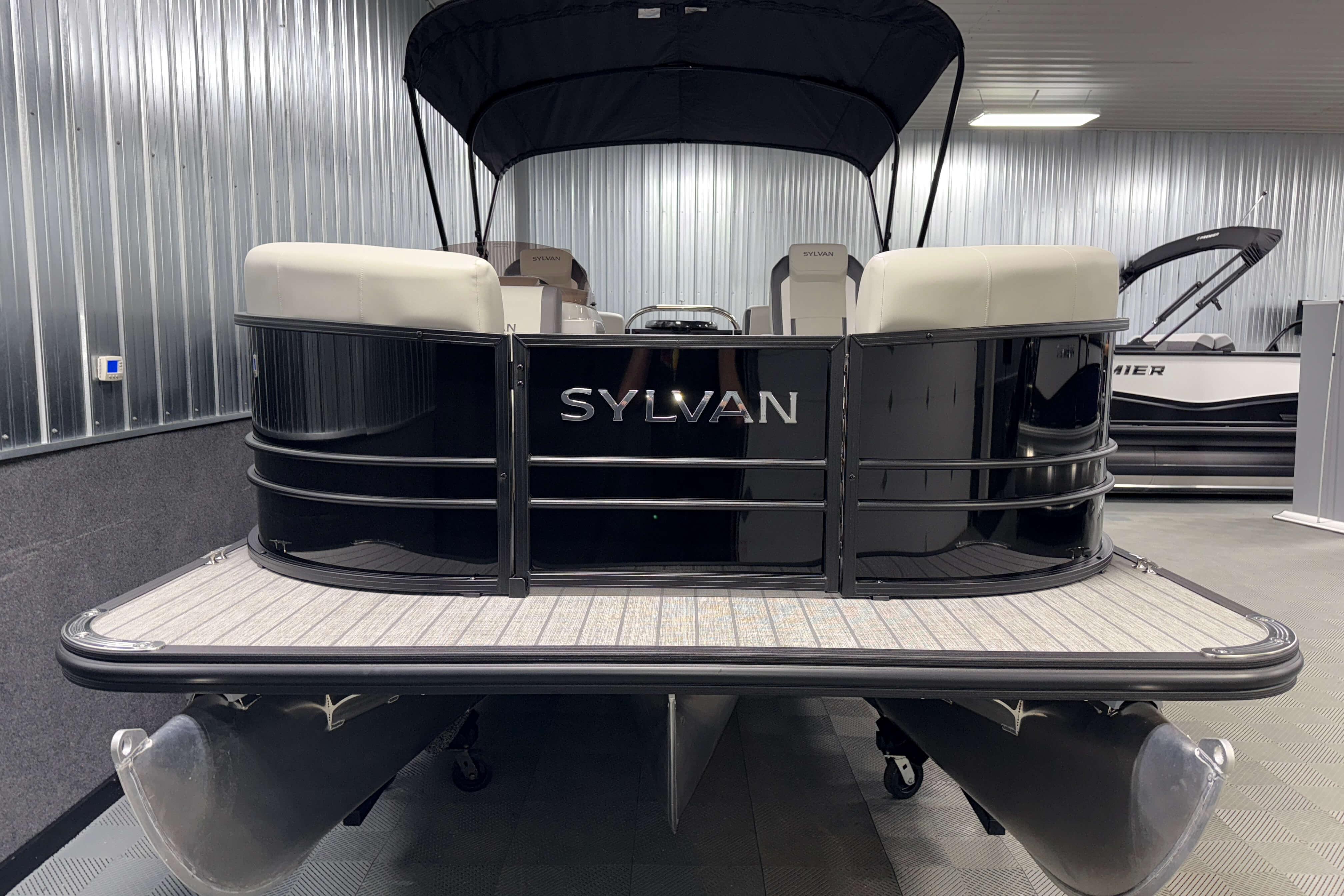2026 Sylvan Mirage X1 pontoon boat in showroom, rear view with canopy.