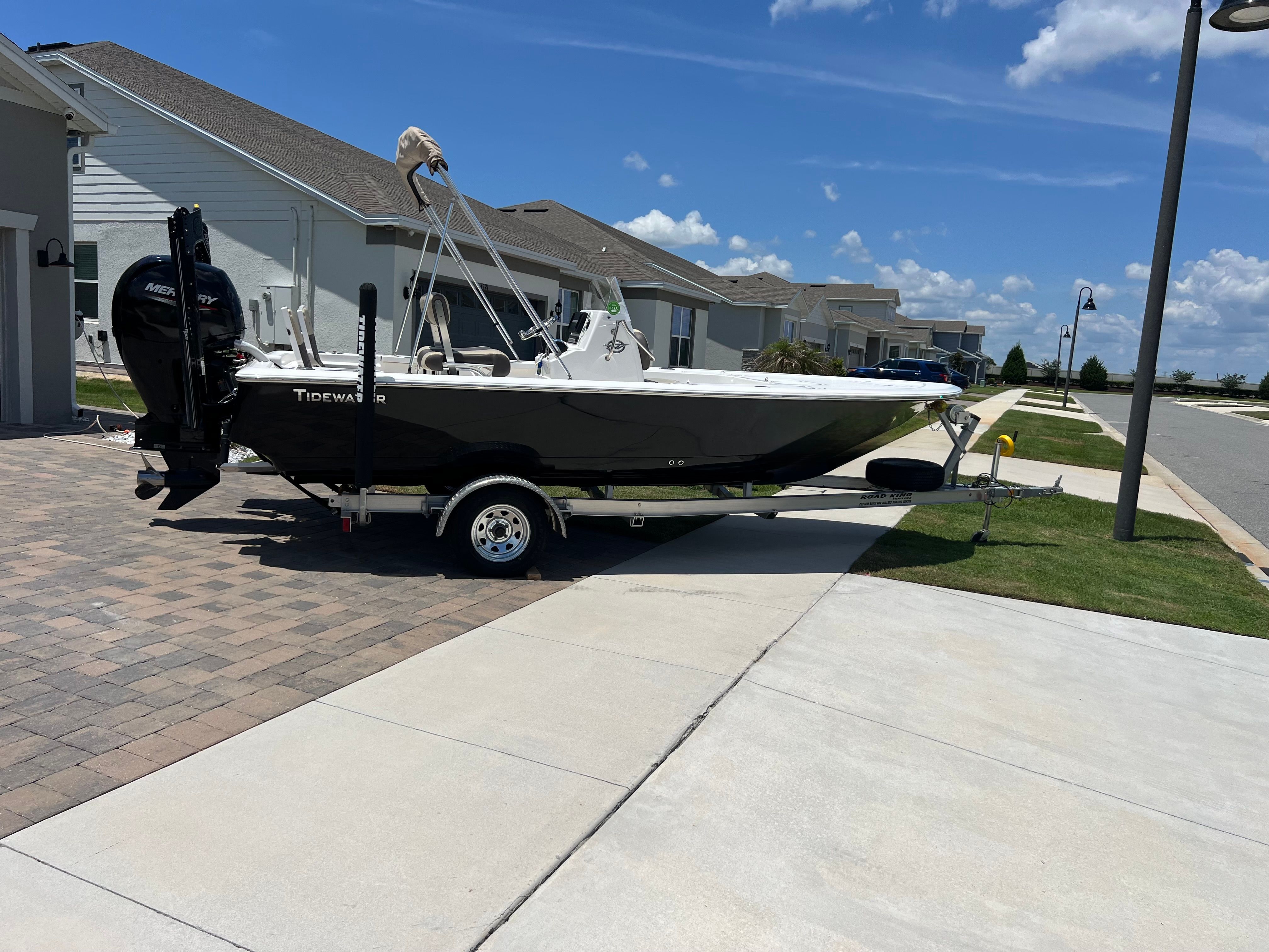 A 2021 Tidewater 1910 Bay Max boat on a trailer in a residential area.