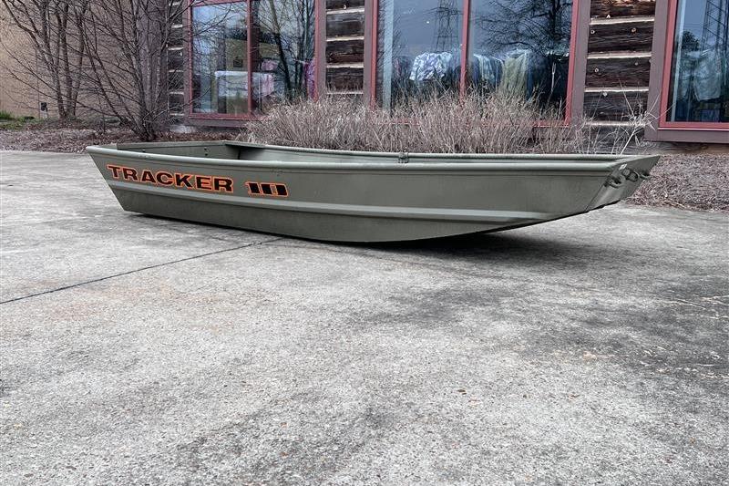 2026 Tracker Grizzly 10 Jon boat on concrete, near building with windows.