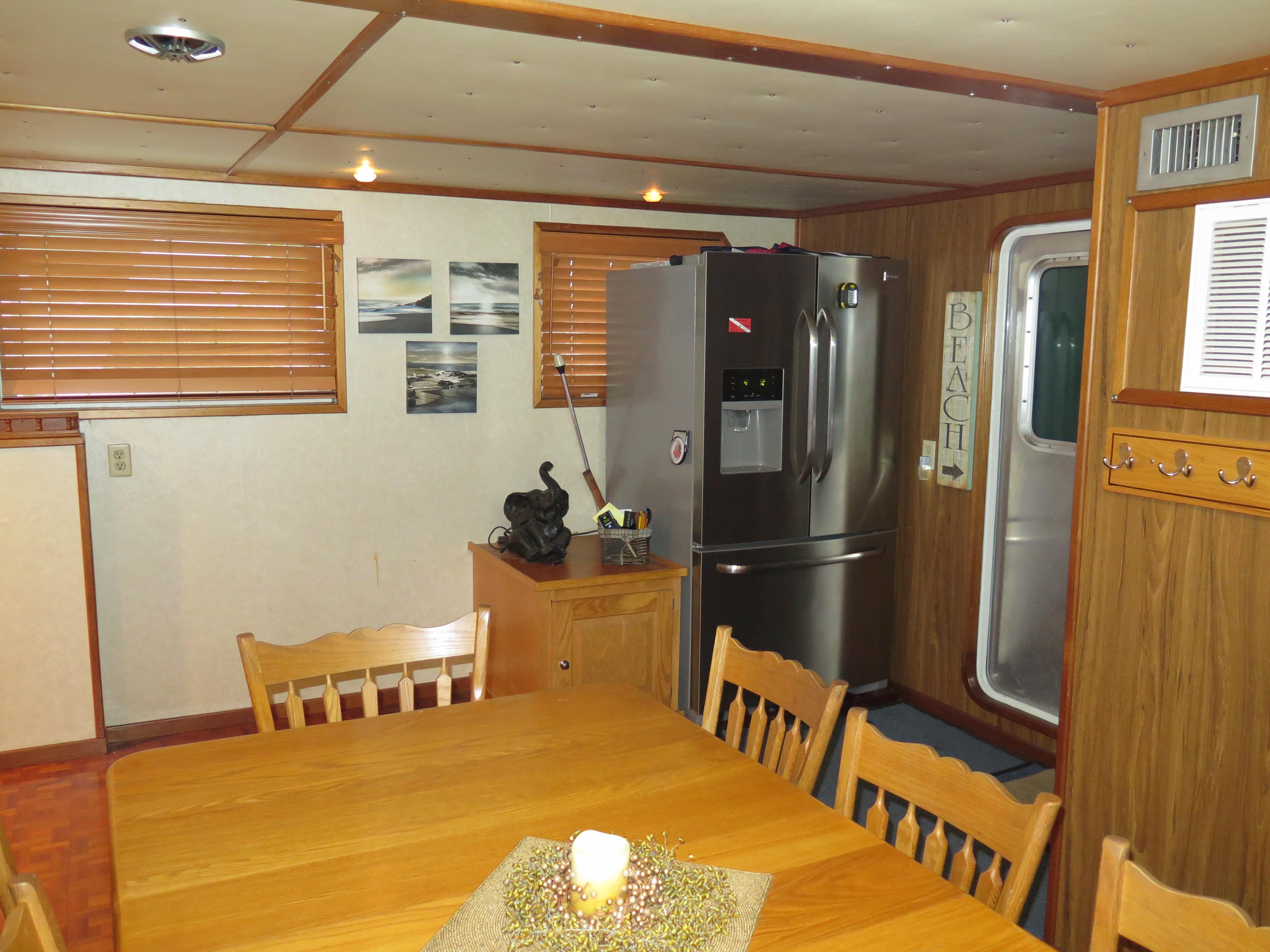 Dining area in a 1998 Rodriquez Custom boat with wooden furniture and modern appliances.