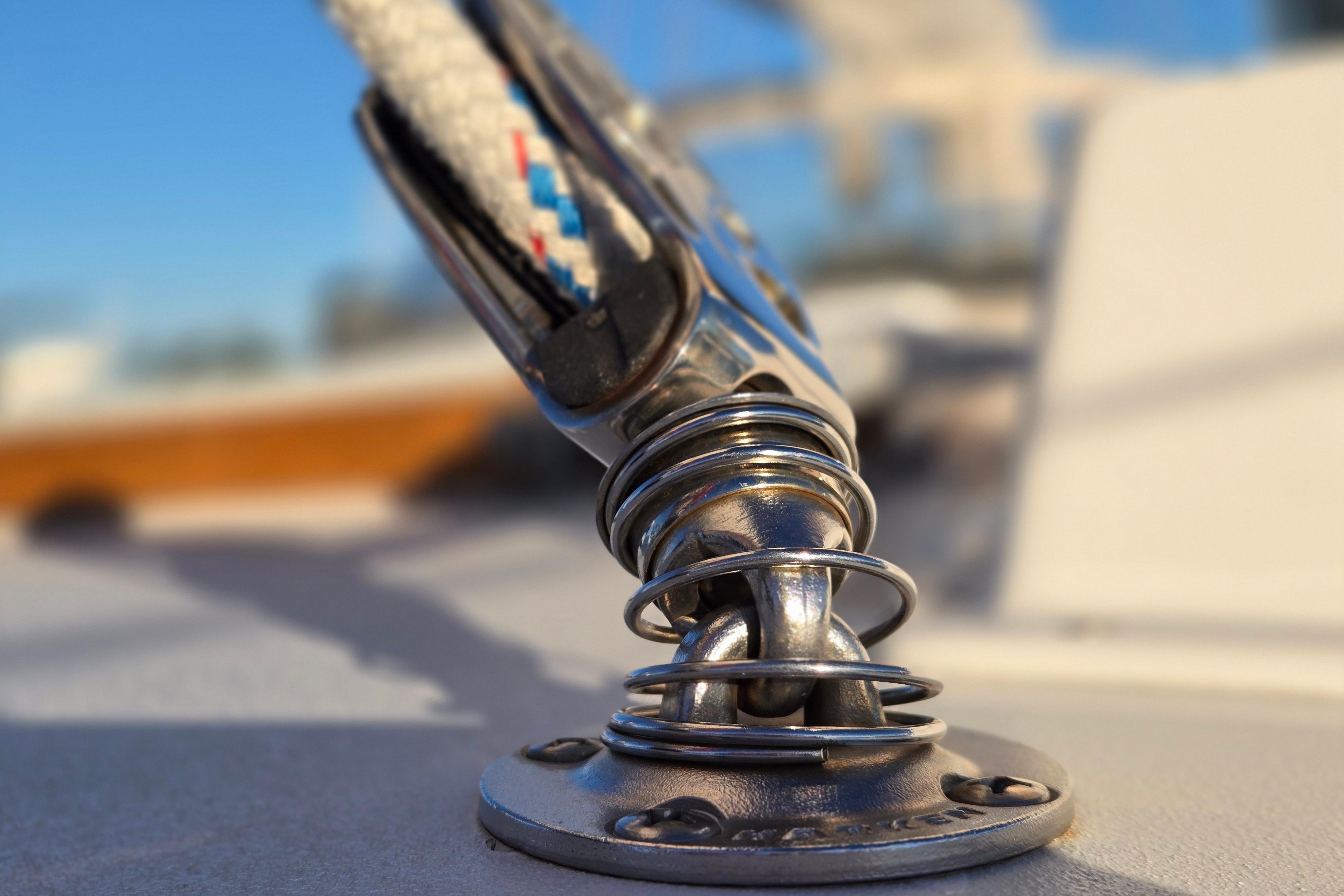 Close-up of a Hinckley Bermuda 40 sailboat's deck fitting, showcasing polished metal and rope detail.