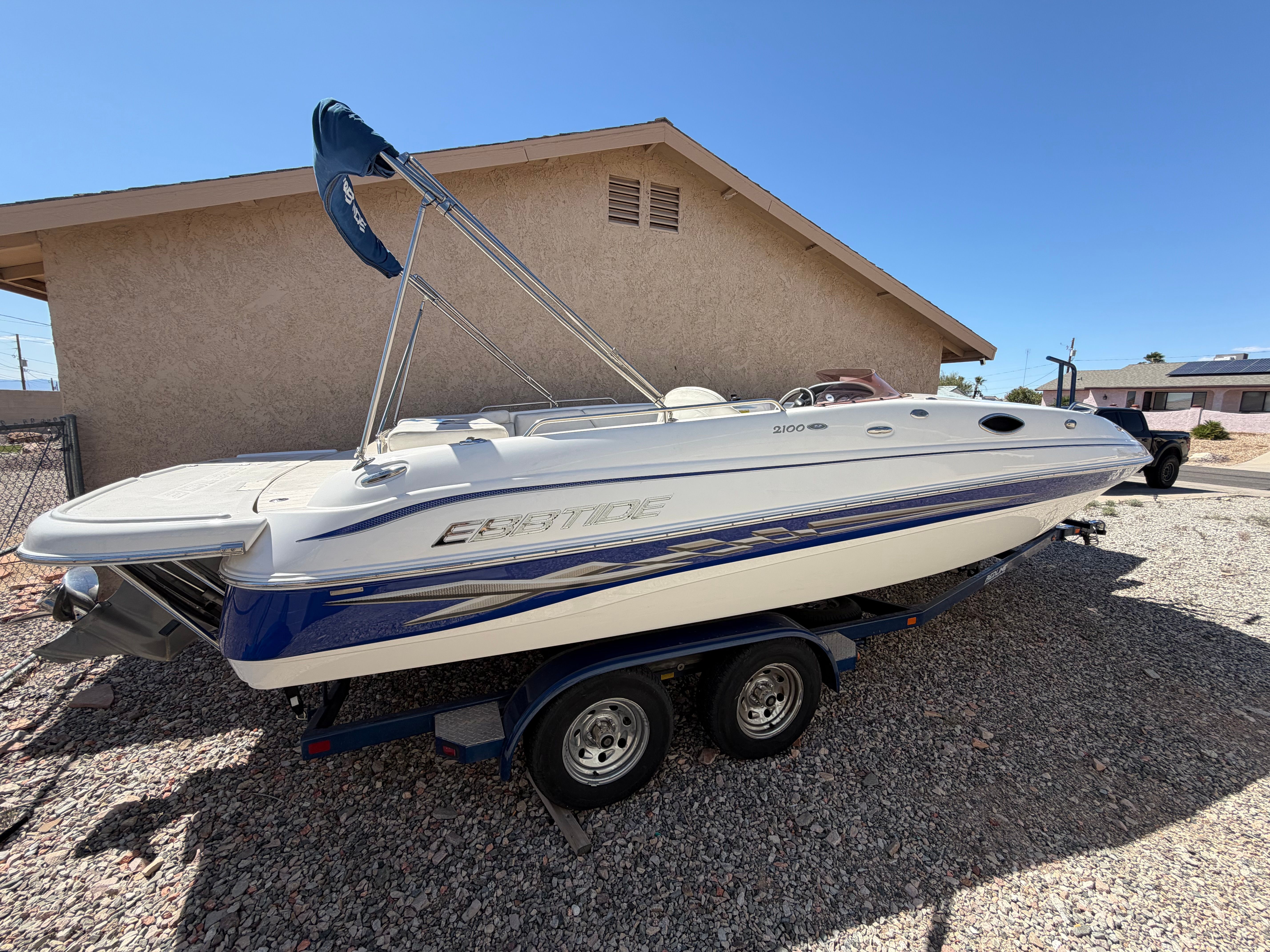 A 2008 Ebbtide 2100 SS Fun Cruiser on a trailer beside a building.