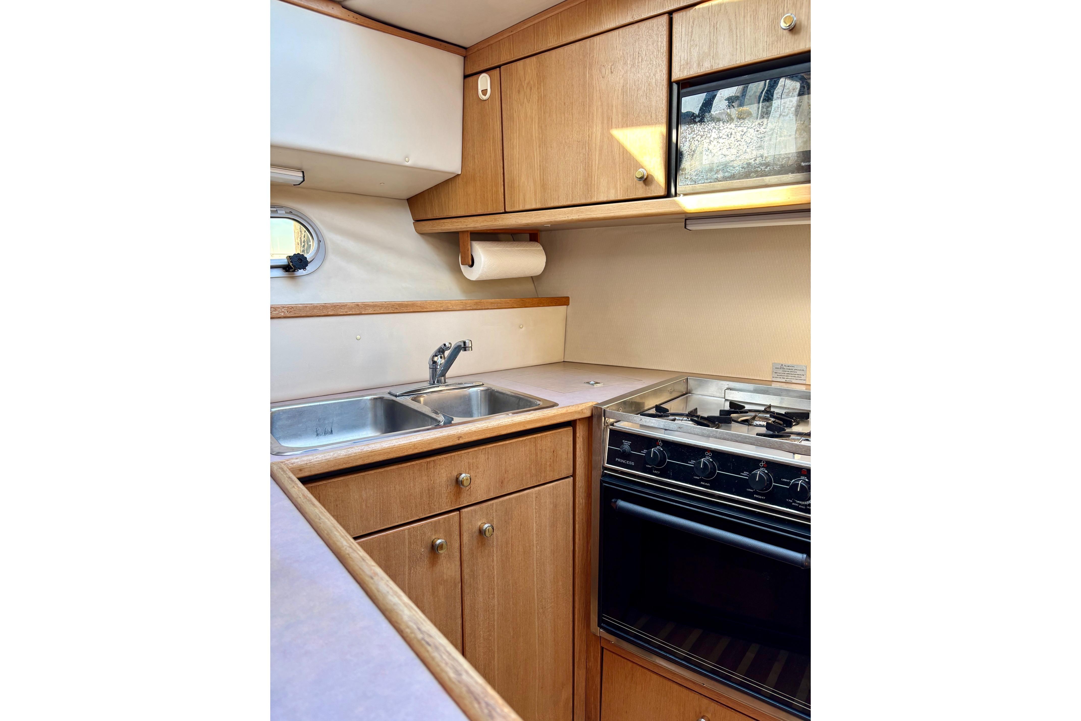1998 Bayliner 3388 Command Bridge Motoryacht kitchen with stove, sink, and wooden cabinets.
