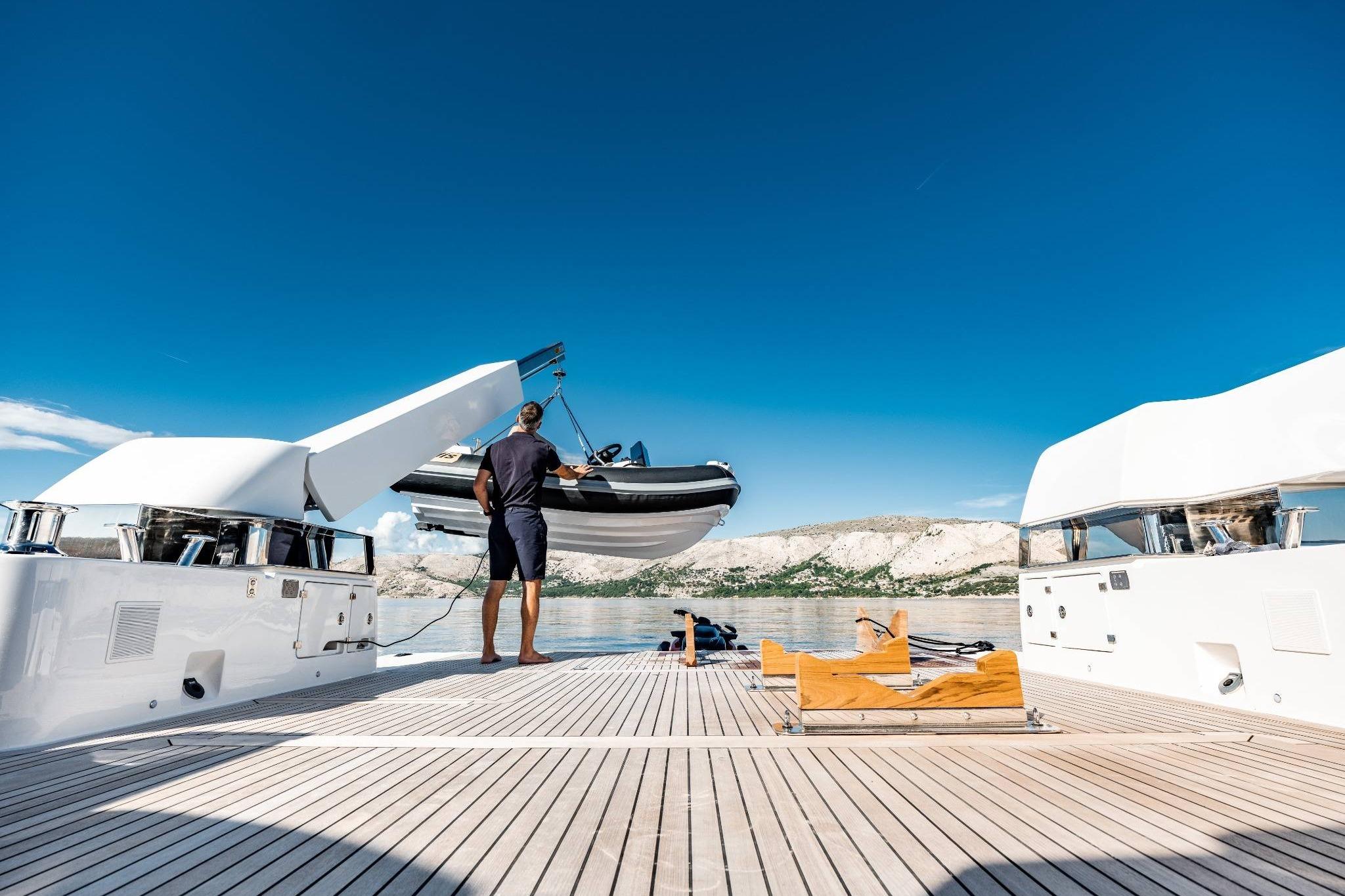 2025 Bluegame BG74 yacht with tender lift on deck, scenic coastal backdrop.