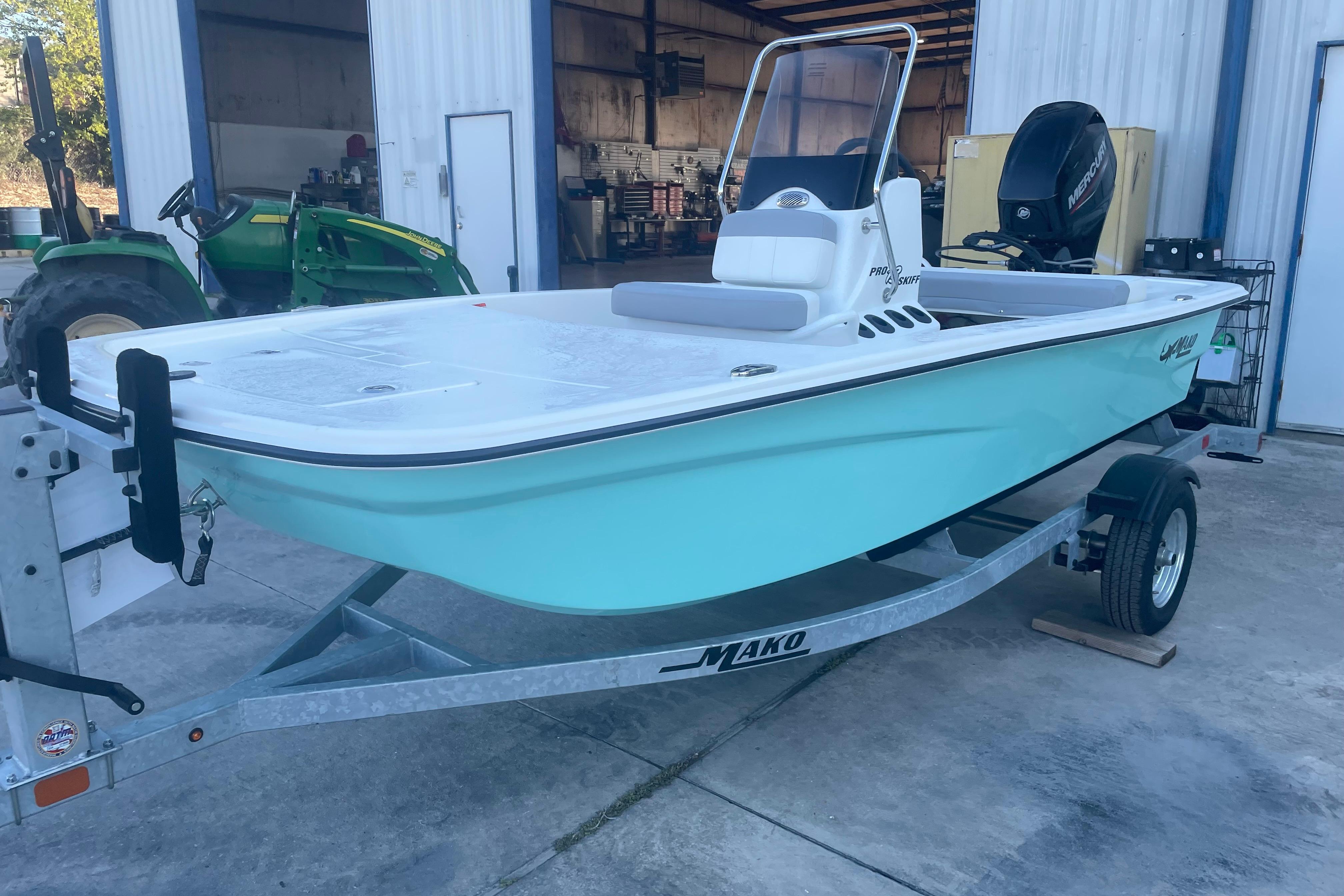 2026 Mako Pro Skiff 13 CC boat on trailer, parked near a green tractor.