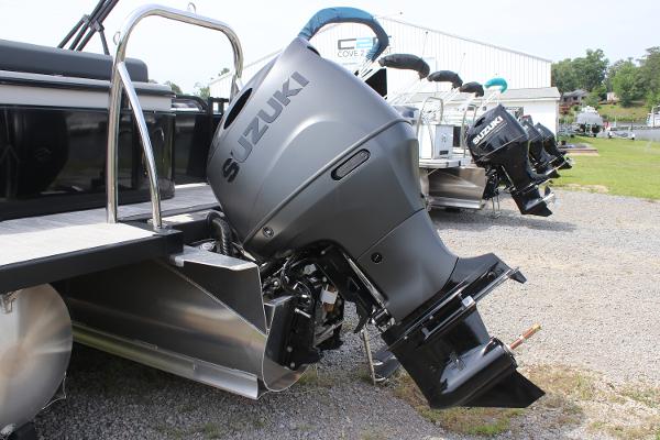 2025 Avalon LSZ Versatile Rear Lounger with Suzuki outboard motor, parked on gravel.