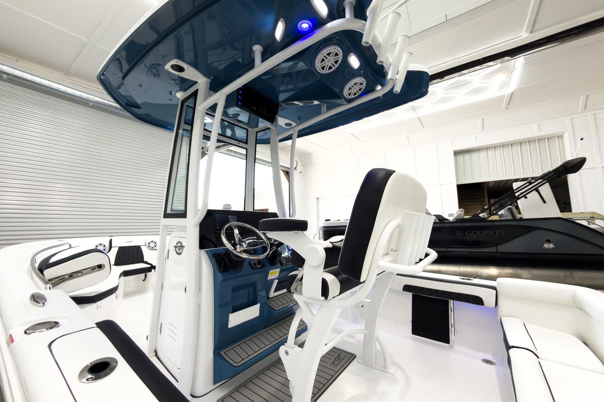 The image shows the cockpit of a 2026 Tidewater 220 LXF boat. It features a modern design with a blue canopy and white seating.