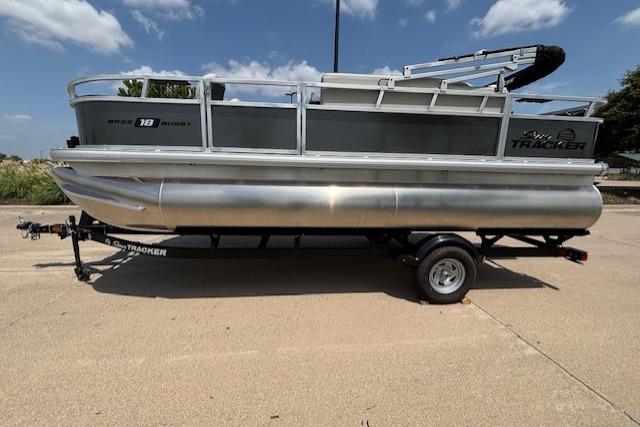 2026 Sun Tracker Bass Buggy 18 DLX pontoon boat on trailer under clear sky.