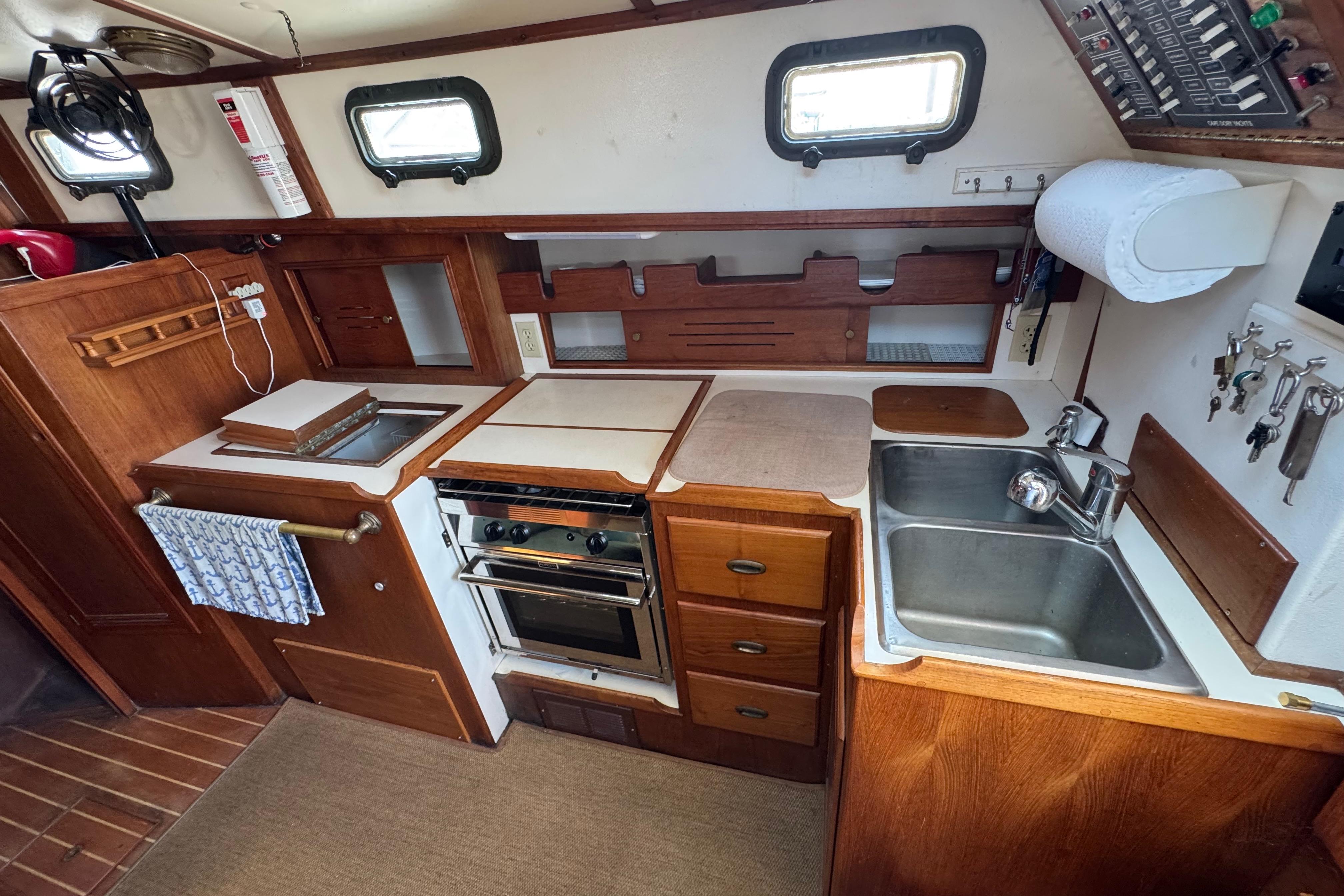 Interior of 1989 Cape Dory 30 Motorsailer kitchen with stove, sink, and wooden cabinetry.