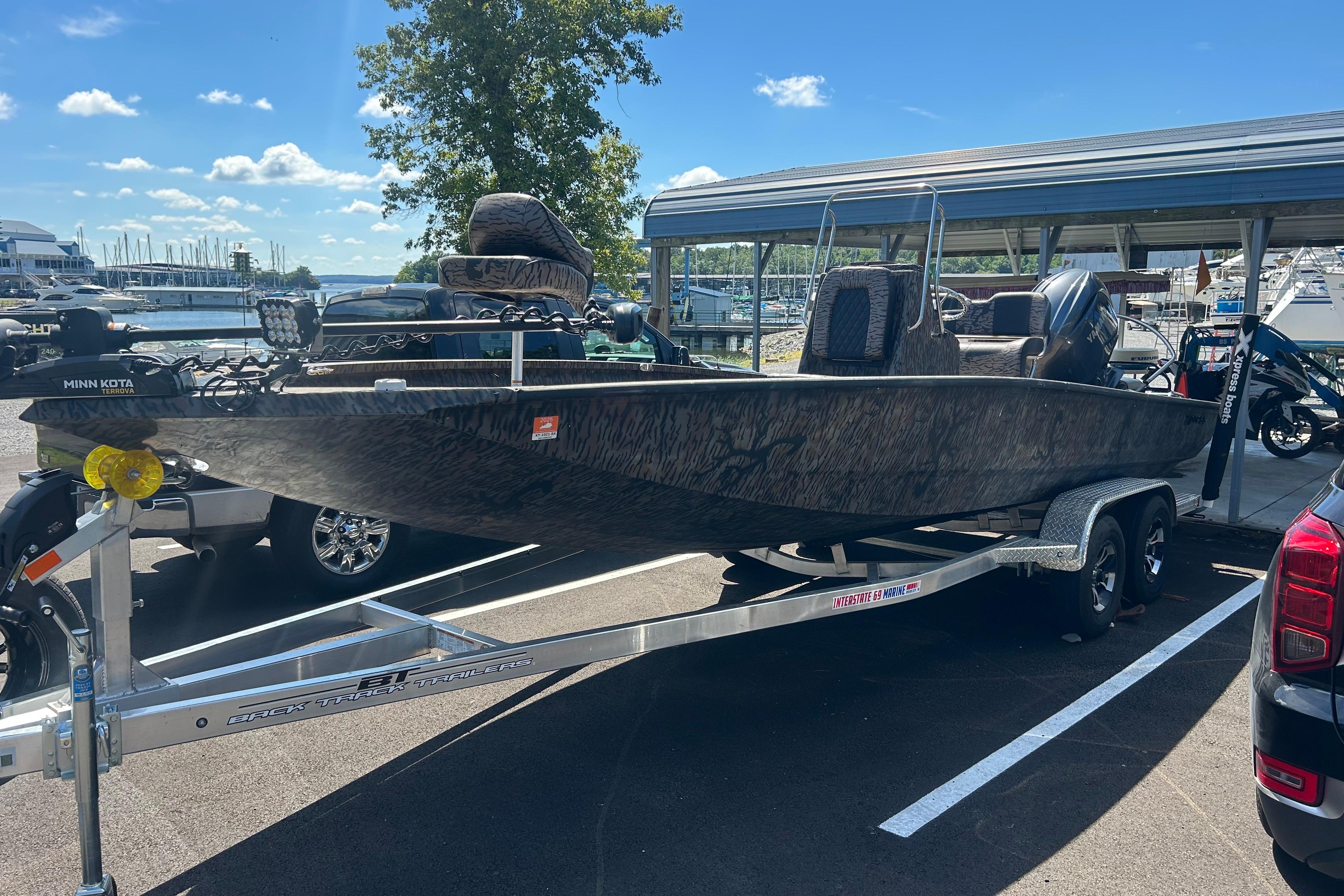 2025 Xpress H22B Bay boat on trailer at marina, sunny day.