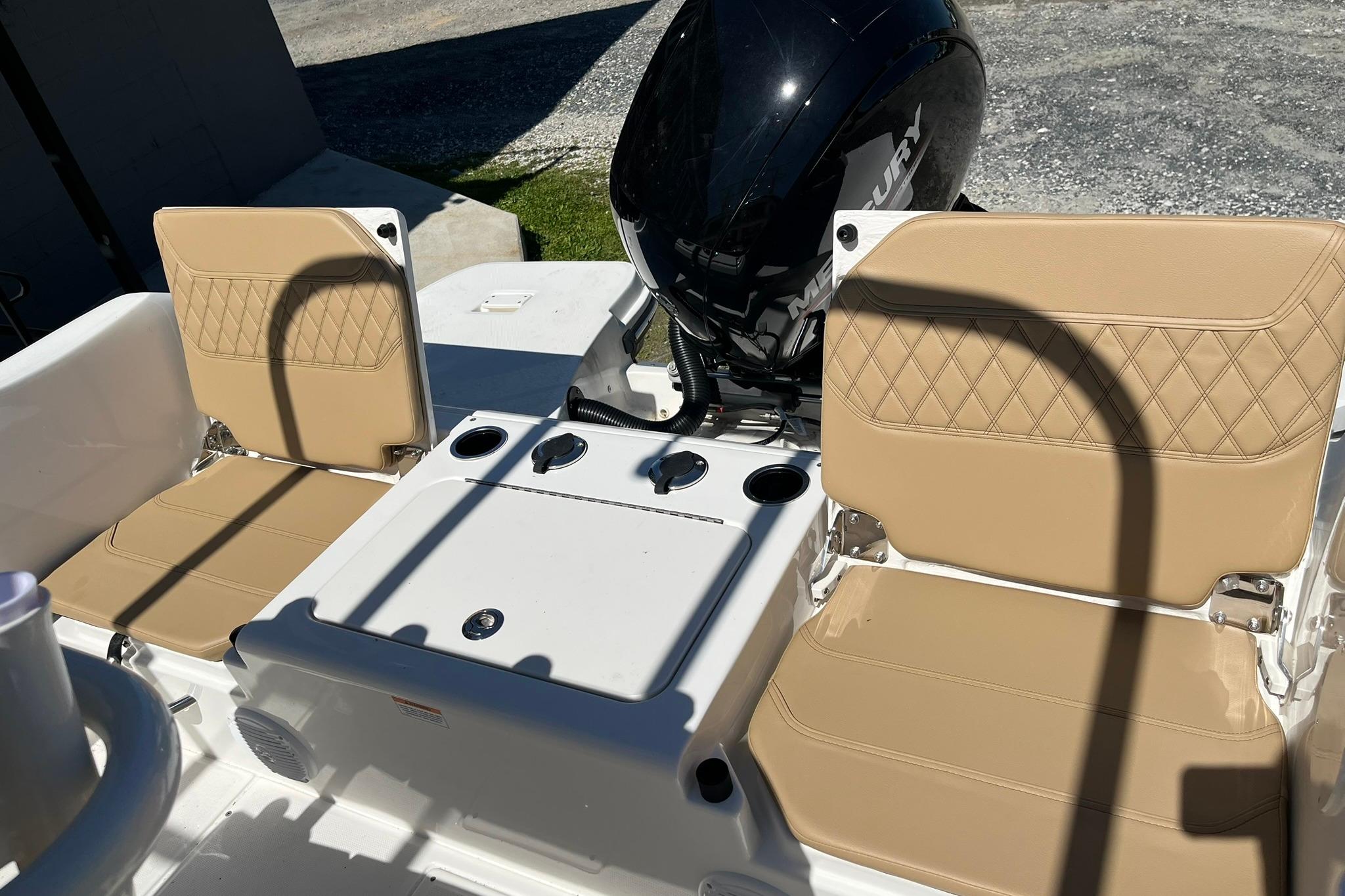 2026 Bayliner Trophy T22CC boat interior with tan cushioned seats and Mercury outboard motor.