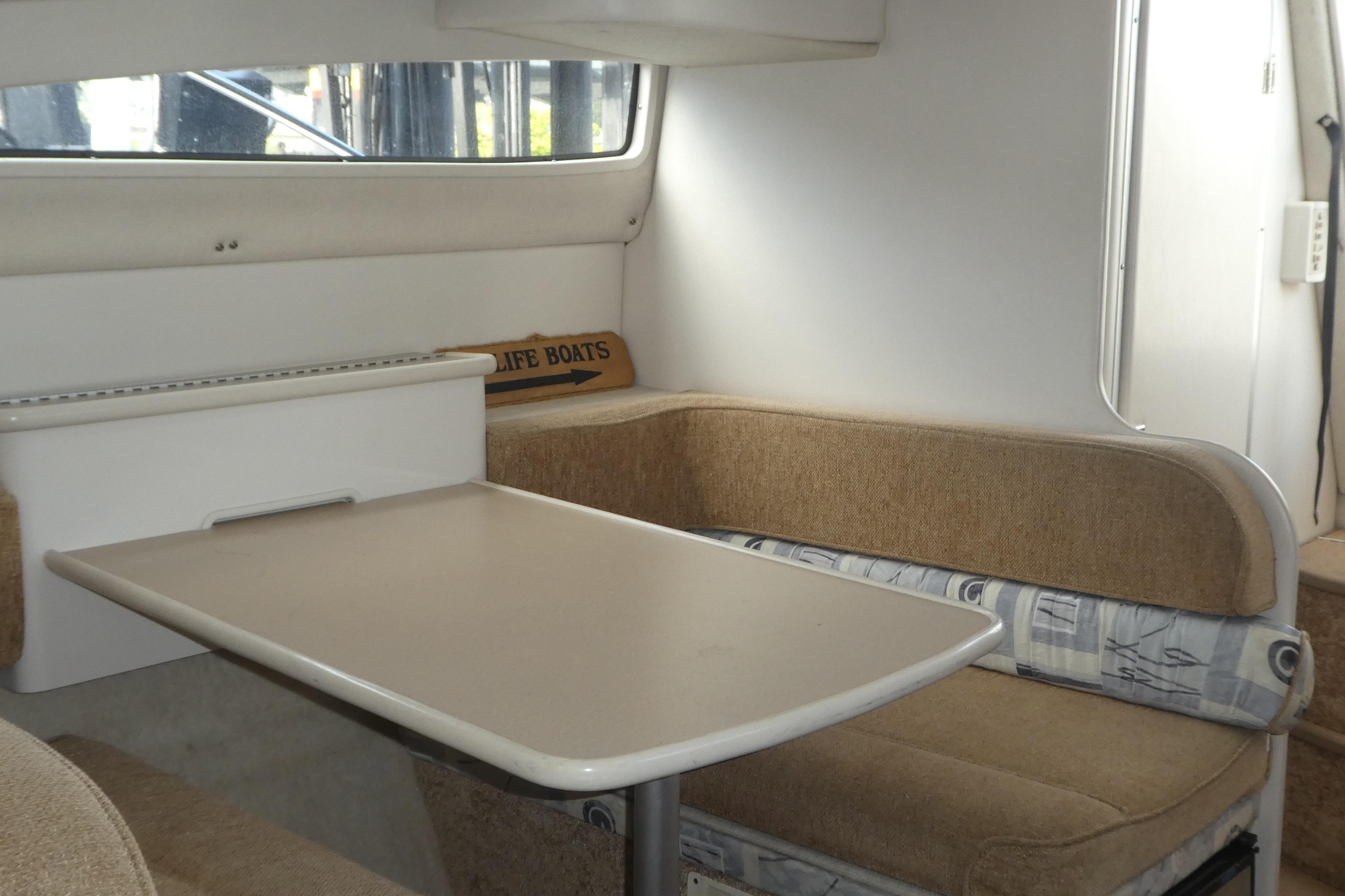 Interior of 2002 Bayliner 2855 Ciera boat with cozy dining area and cushioned seating.