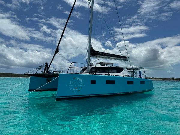 Modern Vision 444 catamaran sailing on clear turquoise waters under a partly cloudy sky.