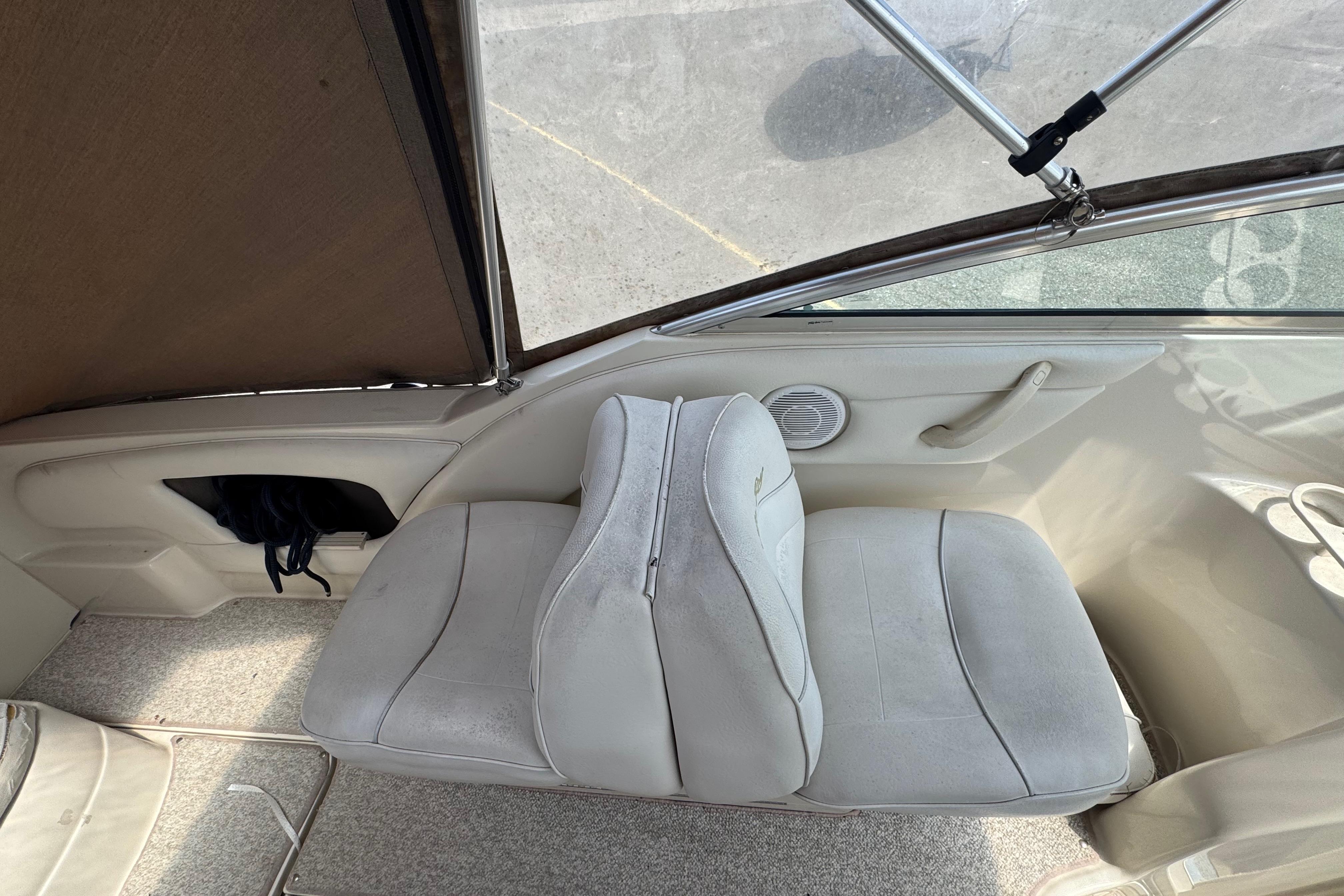 2001 Sea Ray 245 Weekender interior with beige seating and carpeted flooring.