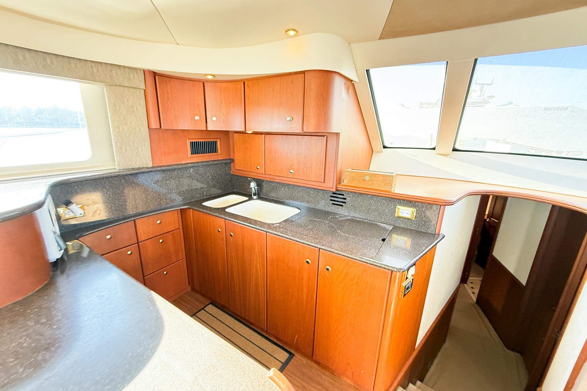 Luxurious 2004 Silverton 48 Convertible yacht kitchen with wood cabinetry and modern countertops.