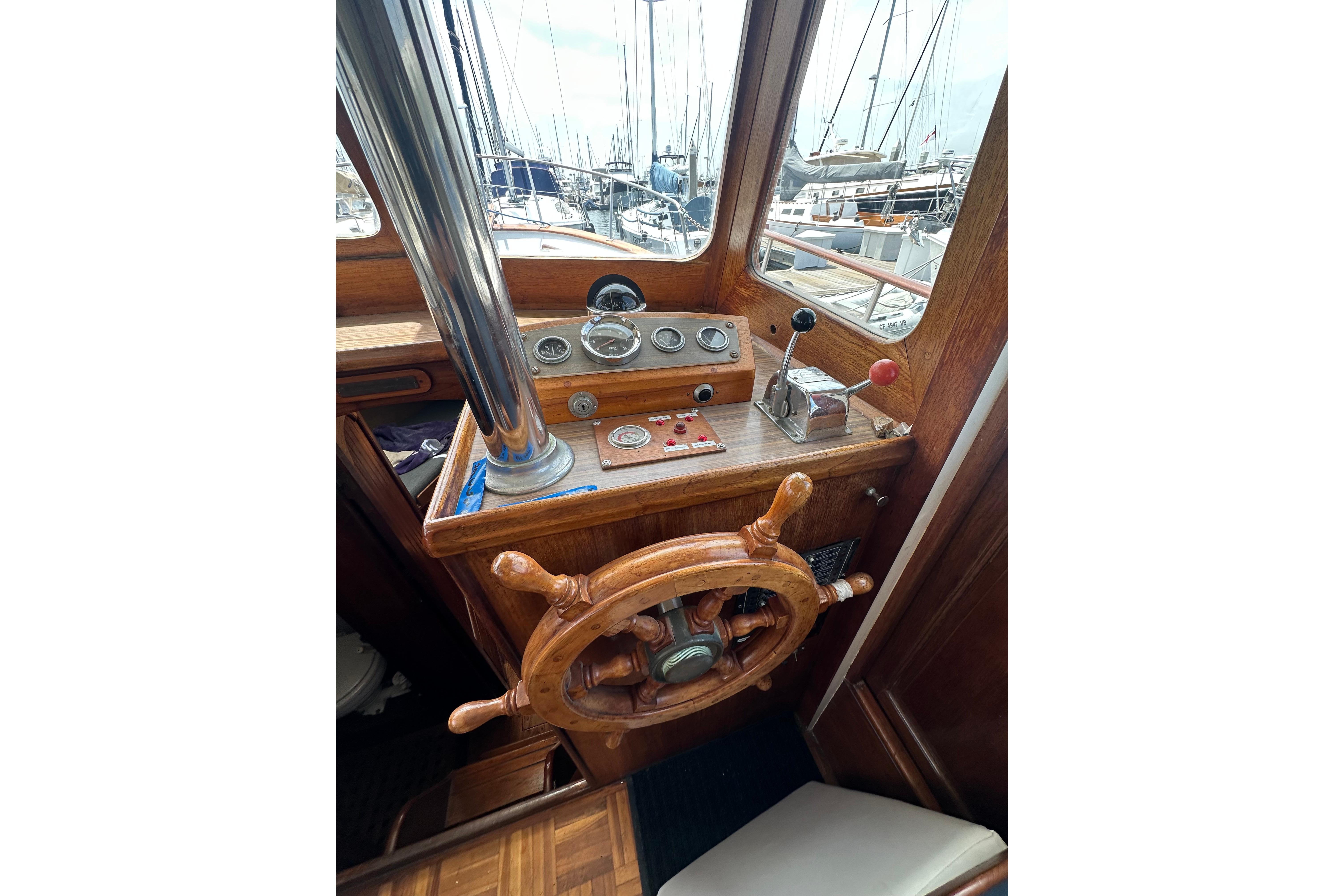 1973 CHB 33 boat helm with wooden steering wheel and control panel in marina setting.