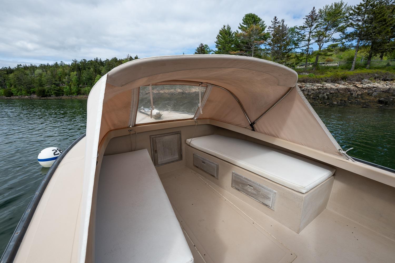 1989 Ellis 24 Open boat interior with canopy, featuring cushioned seating and scenic water view.