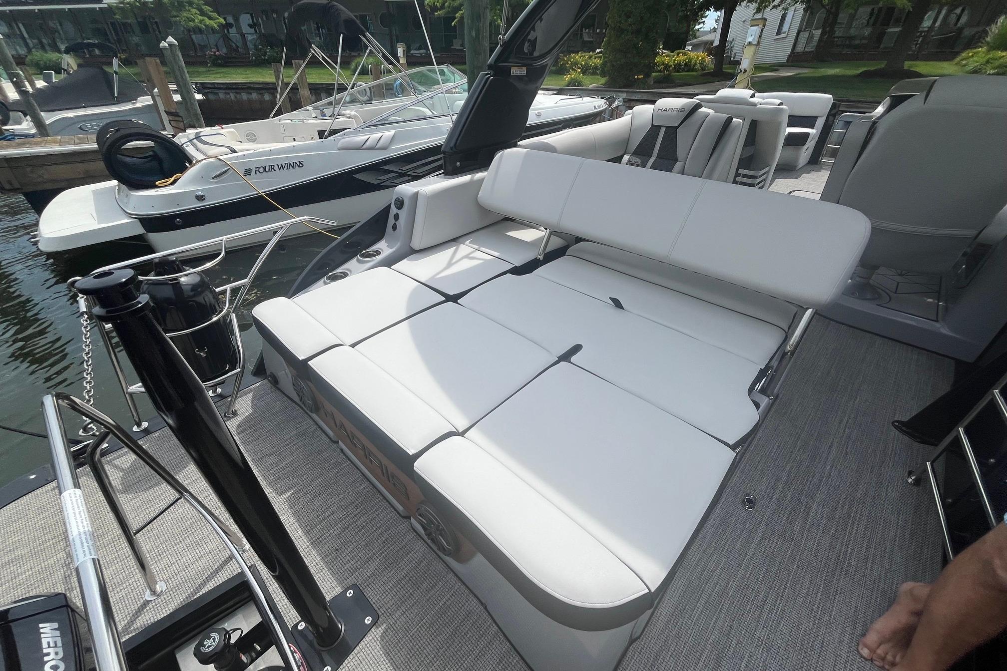 2024 Harris Grand Mariner 250 boat with spacious seating and modern design at a dock.