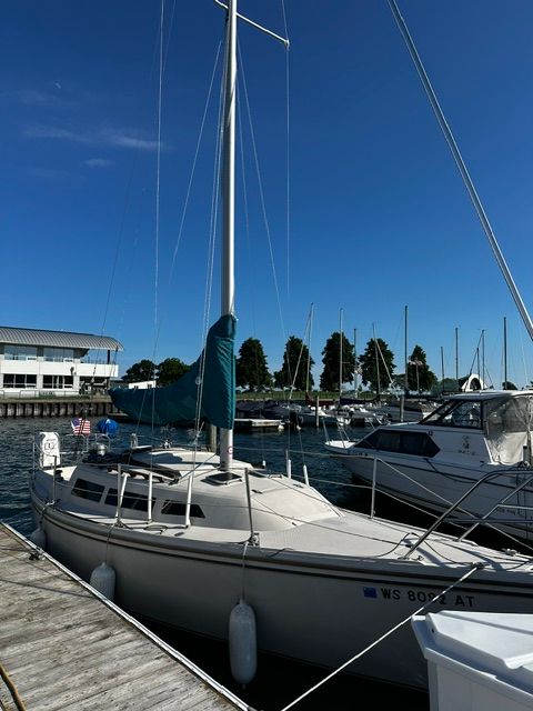 A 1985 Catalina 27 sailboat docked at a marina. Other boats are visible in the background.