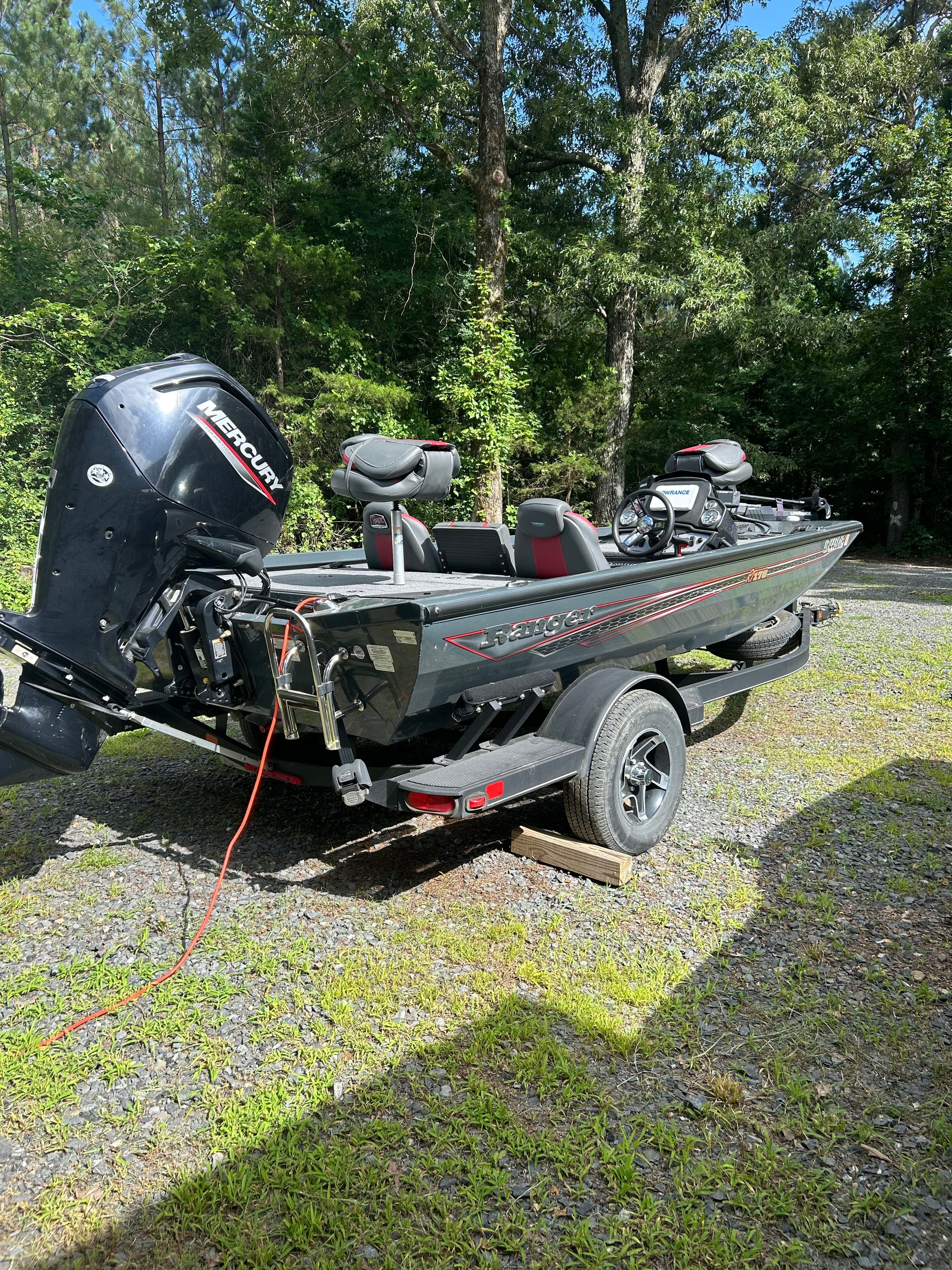 A Ranger RT178 boat on a trailer, surrounded by trees and grass.